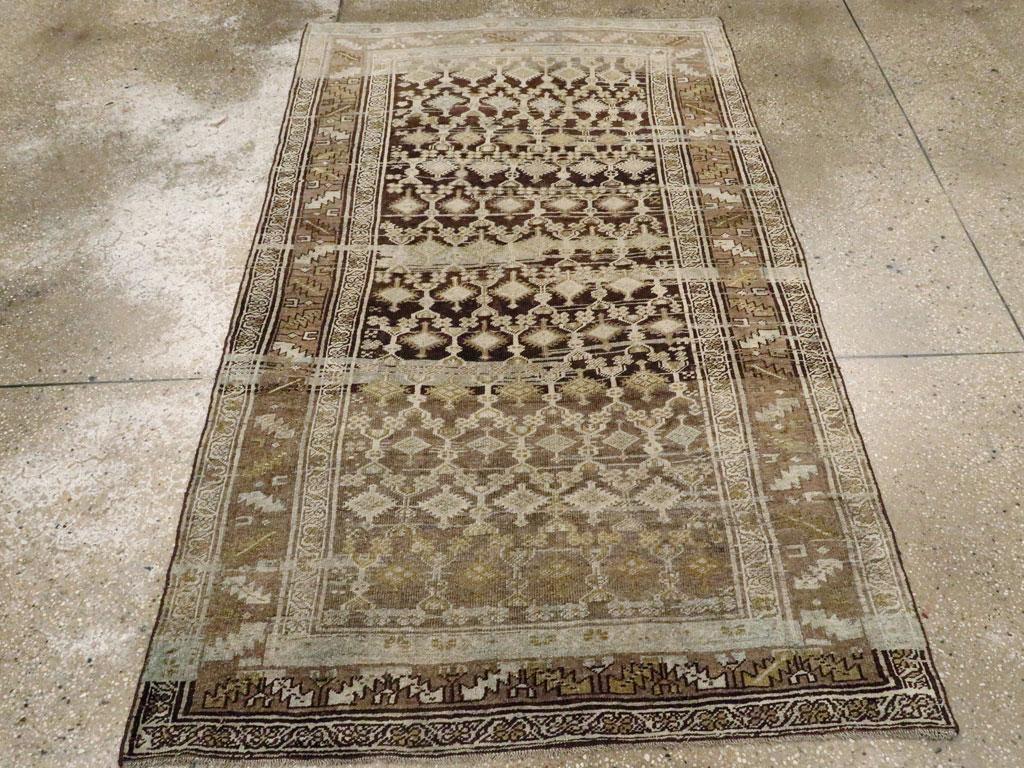 Un ancien tapis d'accent persan kurde. Un treillis ondulé avec de simples bosses de fleurs est placé sur le fond amusant de charbon de bois abrasé et reçoit des losanges naïfs à double fleuron. La bordure brun-rose présente le motif caucasien de