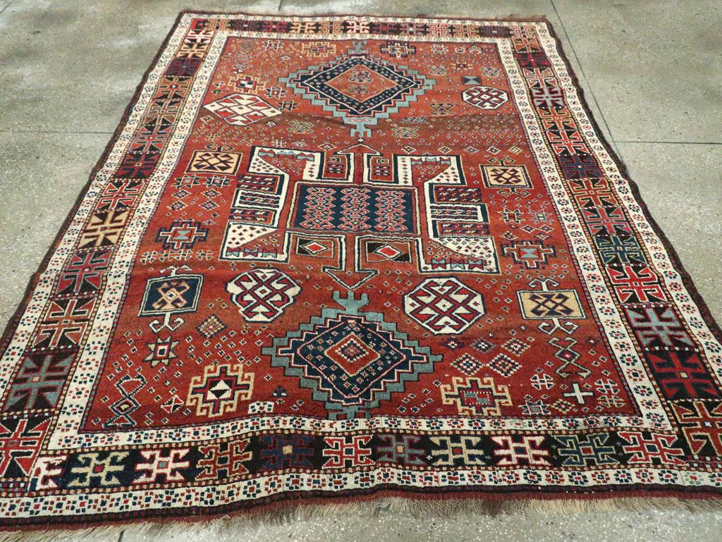An antique Persian Kurdish accent rug. Form NE Persia, this attractive, nomadic all wool rug displays a blood red madder field with a central eccentric ivory medallion between steppe light blue lozenges. The field s filled with a scatter of