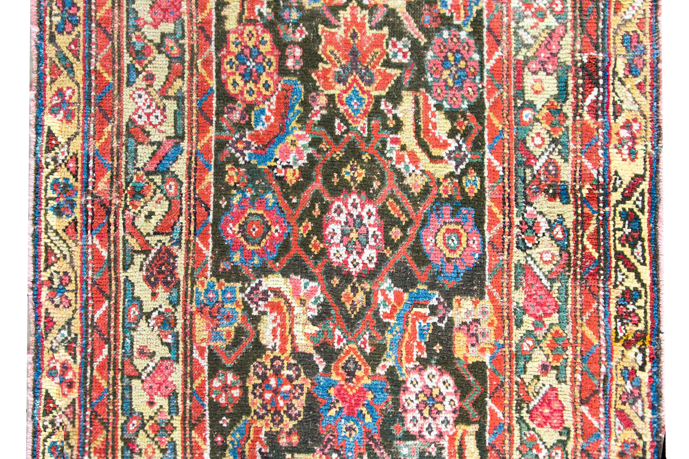 A wonderful early 20th century Persian Kurdish rug with an all-over floral trellis pattern with large flowers and leaves woven in myriad colors including crimson, indigo, gold, pink and green, and all surrounded by a complex border with several
