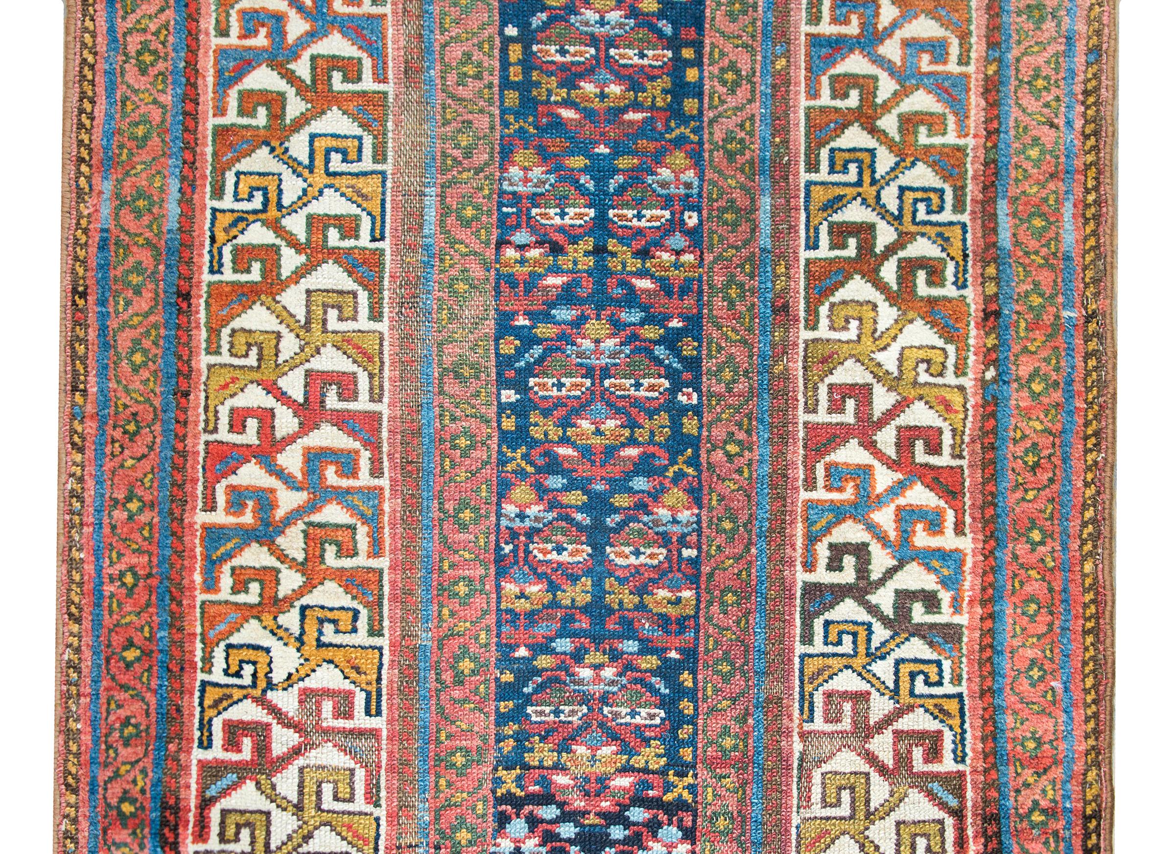 A wonderful early 20th century Persian Kurdish runner with a narrow stylized floral pattern in the center, and surrounded by a wide complex border with a wide stylized floral pattern flanked by pairs of petite geometric and floral patterned stripes.