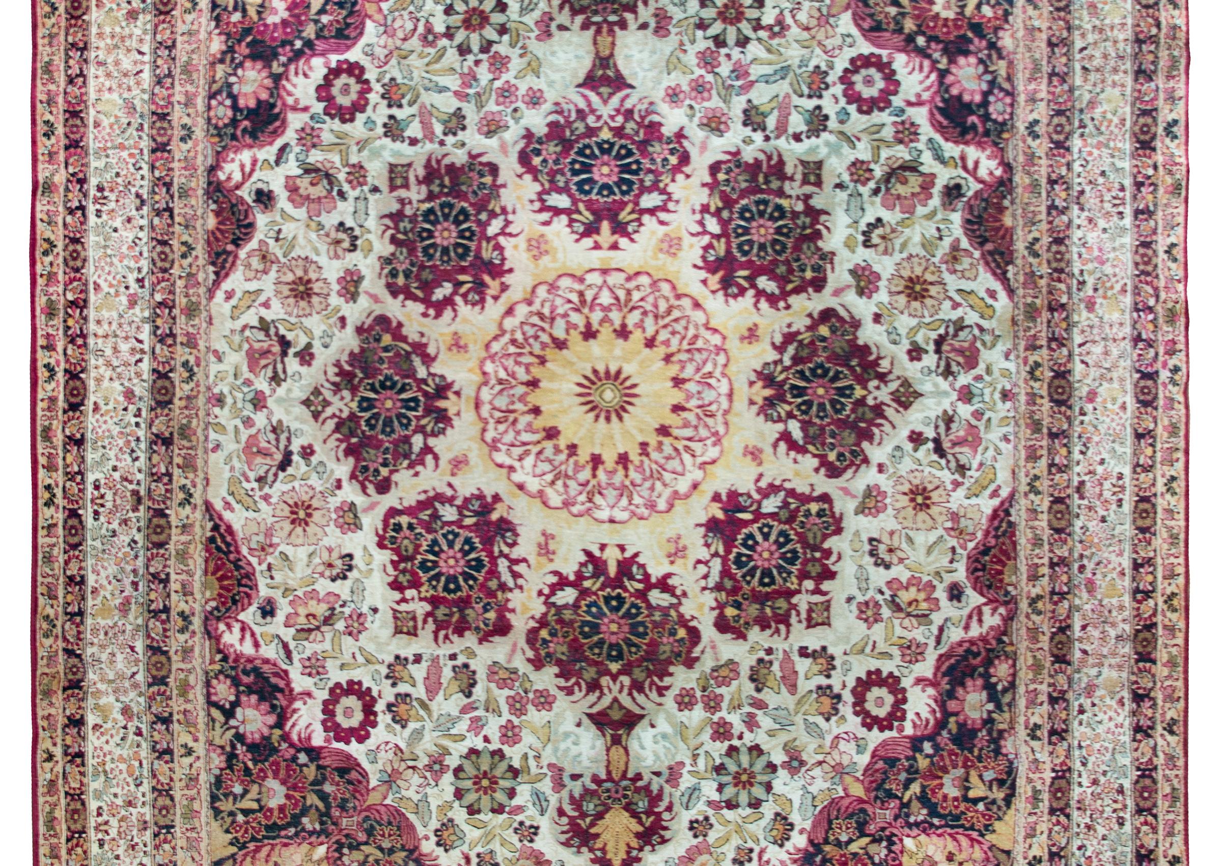 An early 20th century Persian Lavar Kirman rug with the most unique central medallion surrounded by eight individual floral medallions living amidst a field of more large and small scale flowers.  The border is complex with a wide central intensely