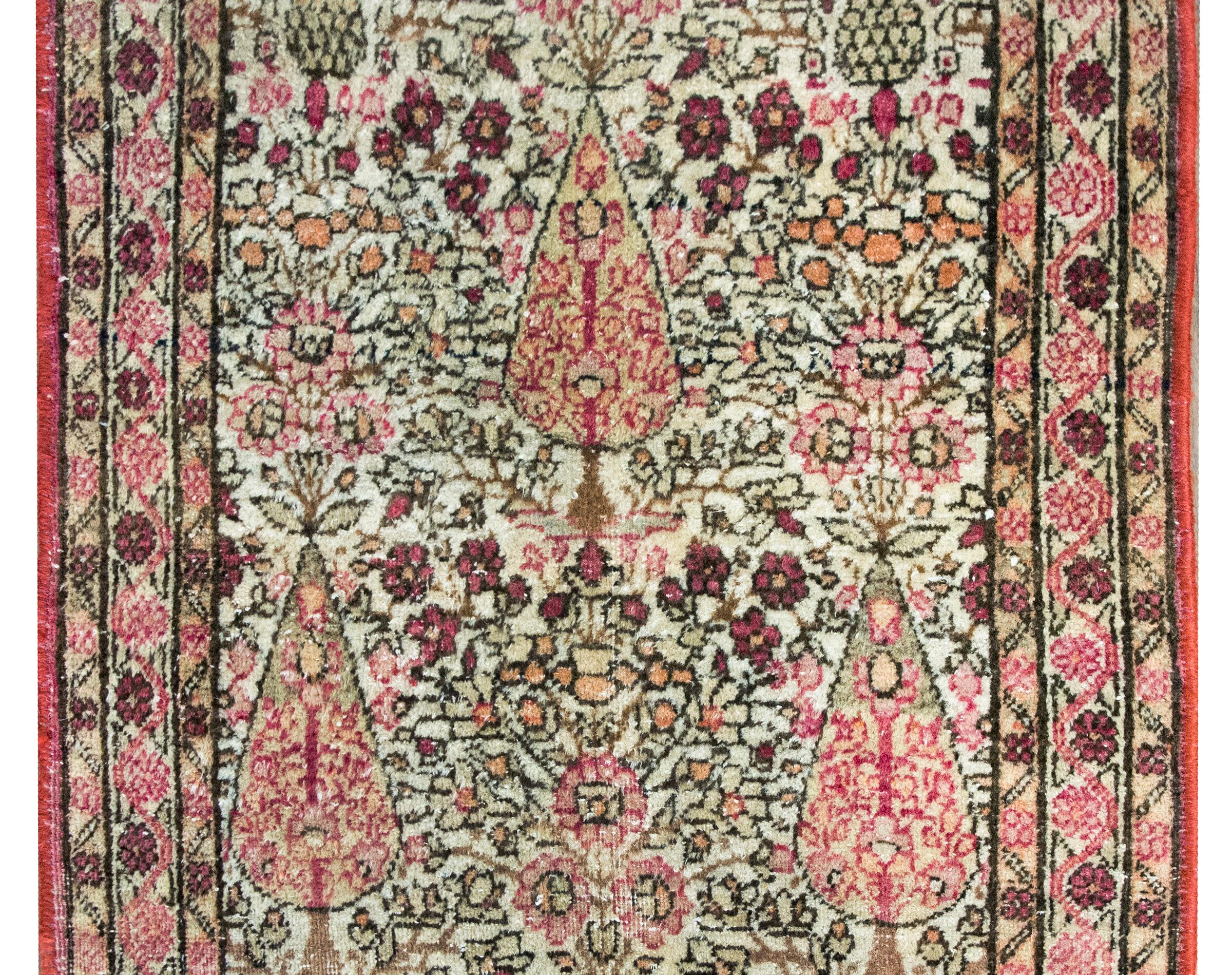Preciosa alfombra persa Lavar Kirman de principios del siglo XX, con tres grandes cipreses que viven en medio de un campo densamente poblado de flores y enredaderas, rodeados por un complejo borde con tres pequeñas franjas con motivos florales y