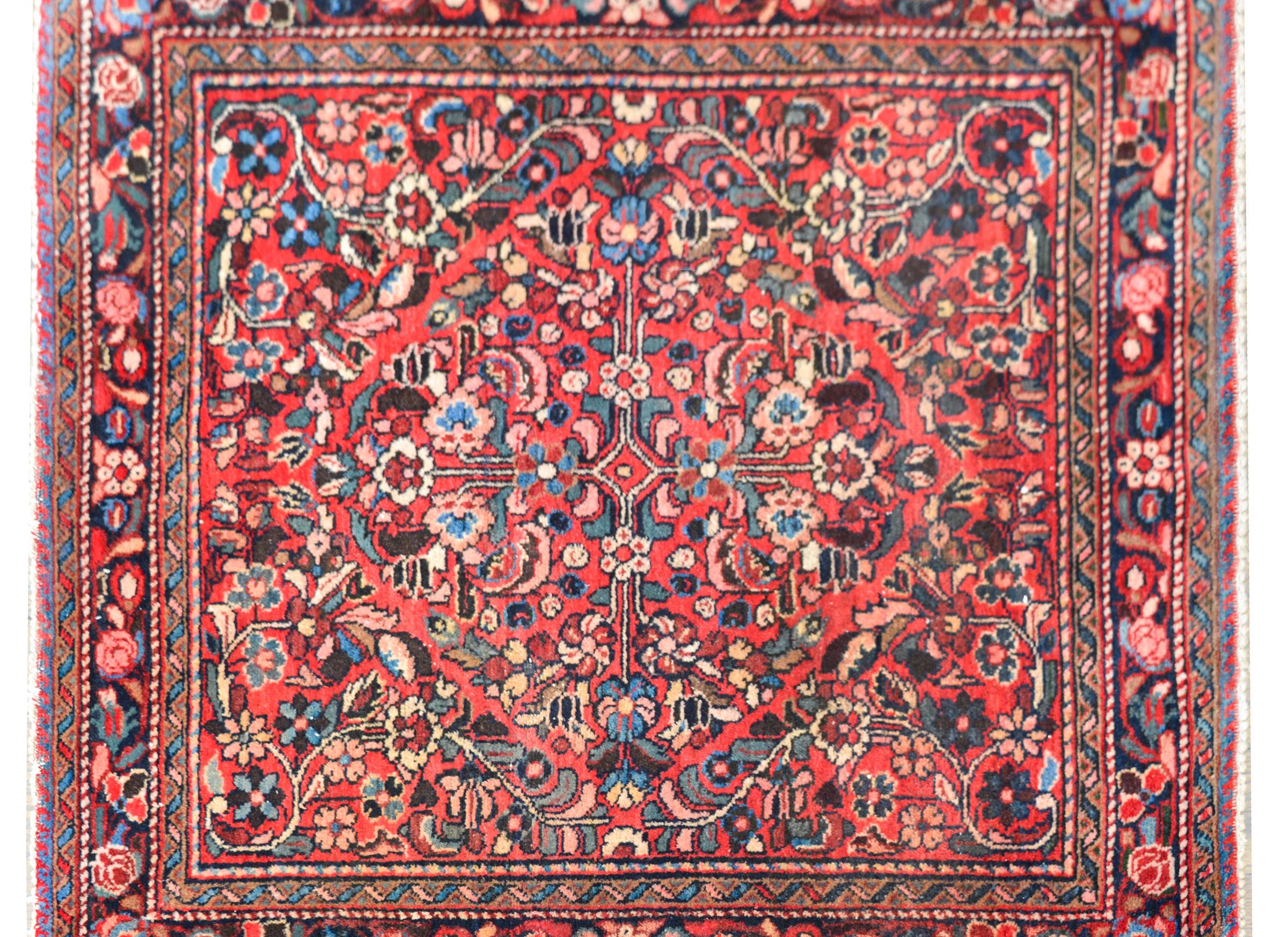 A wonderful early 20th century Persian Lilihan rug of unusual size with a mirrored floral pattern woven in myriad colors including pink, green, light indigo, crimson, and white, and all set against a coral colors background. The border is complex