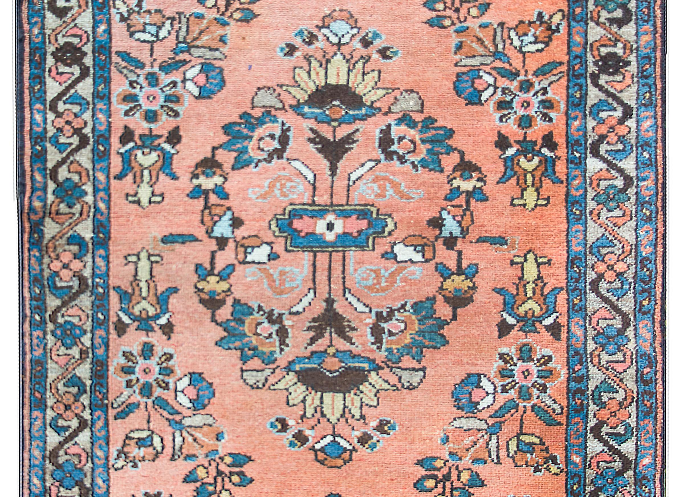 Un tappeto persiano Lilihan dell'inizio del XX secolo con un motivo floreale a specchio meravigliosamente reso in indaco, oro, crema e rosa, su uno sfondo color corallo e circondato da un bordo con fiori stilizzati e tralci di vite a scorrimento