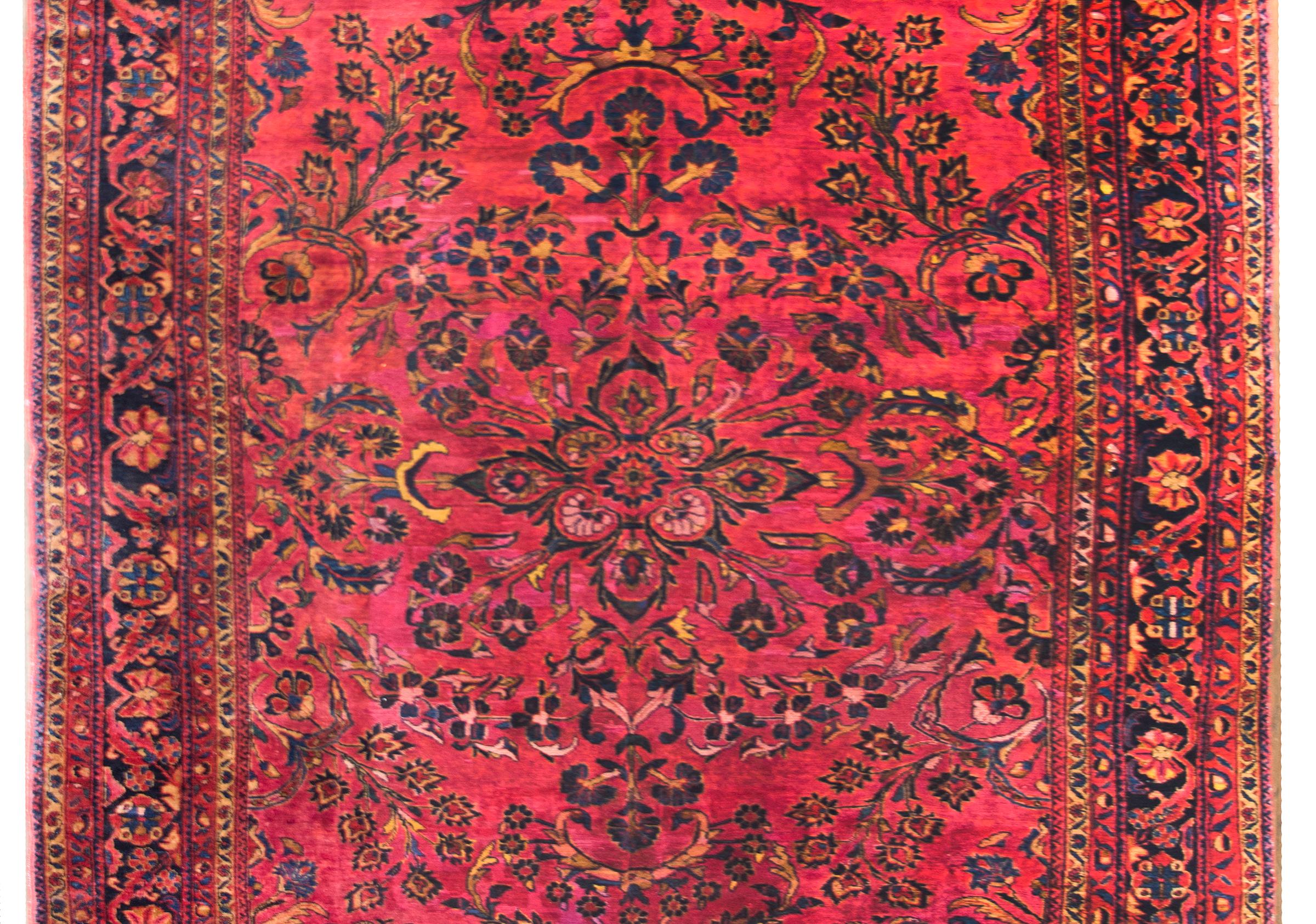 A beautiful early 20th century Persian Lilihan rug with a central floral medallion living amidst a field of more flowers and scrolling vines, surrounded by a complex border with a central repeated floral patterned stripe flanked by pairs of matching