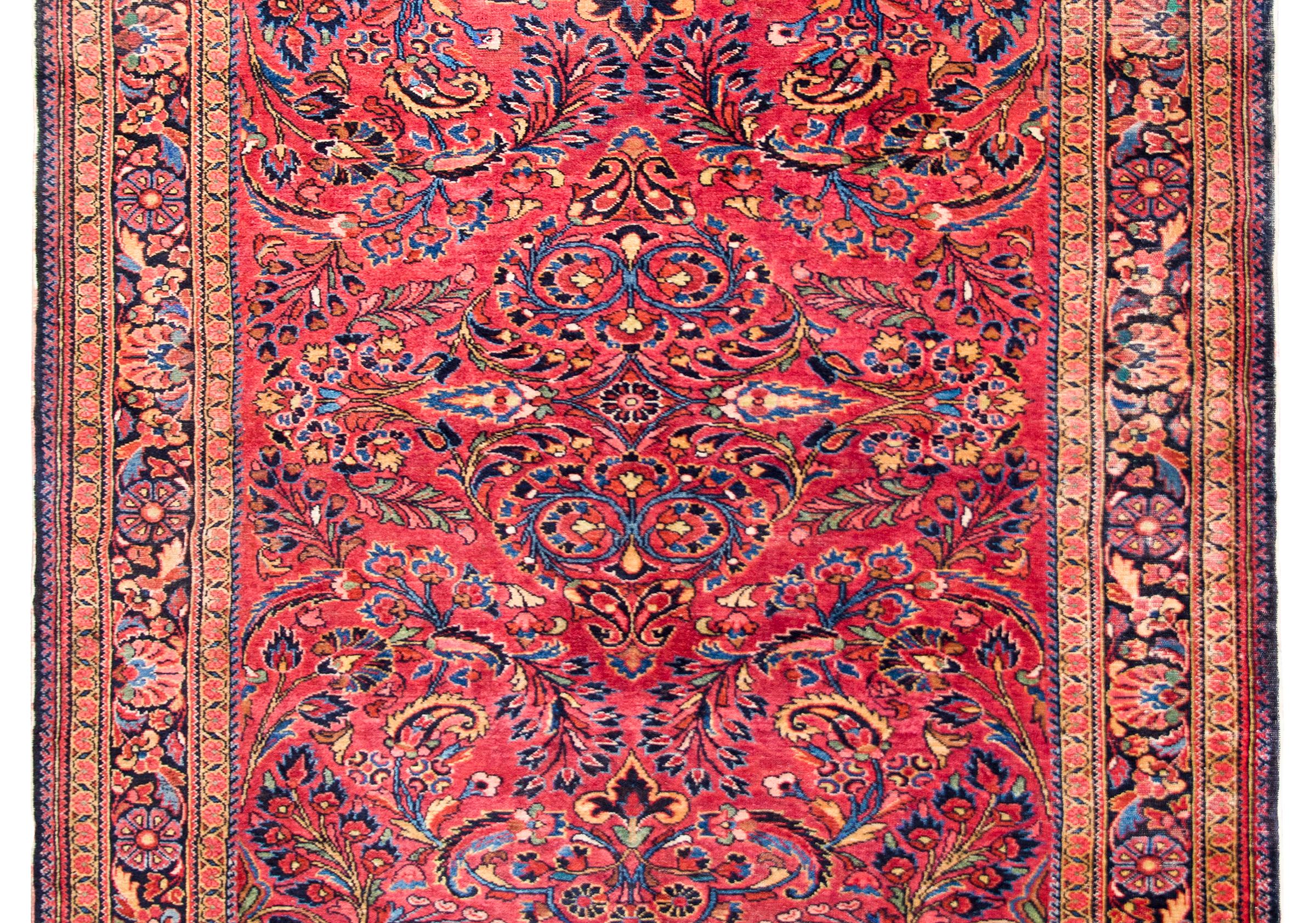 A beautiful early 20th century Persian Lilihan rug woven with a traditional mirrored floral pattern containing myriad flower and scrolling vines, surrounded by a wide repeated floral patterned border, and all woven in traditional Lilihan colors of