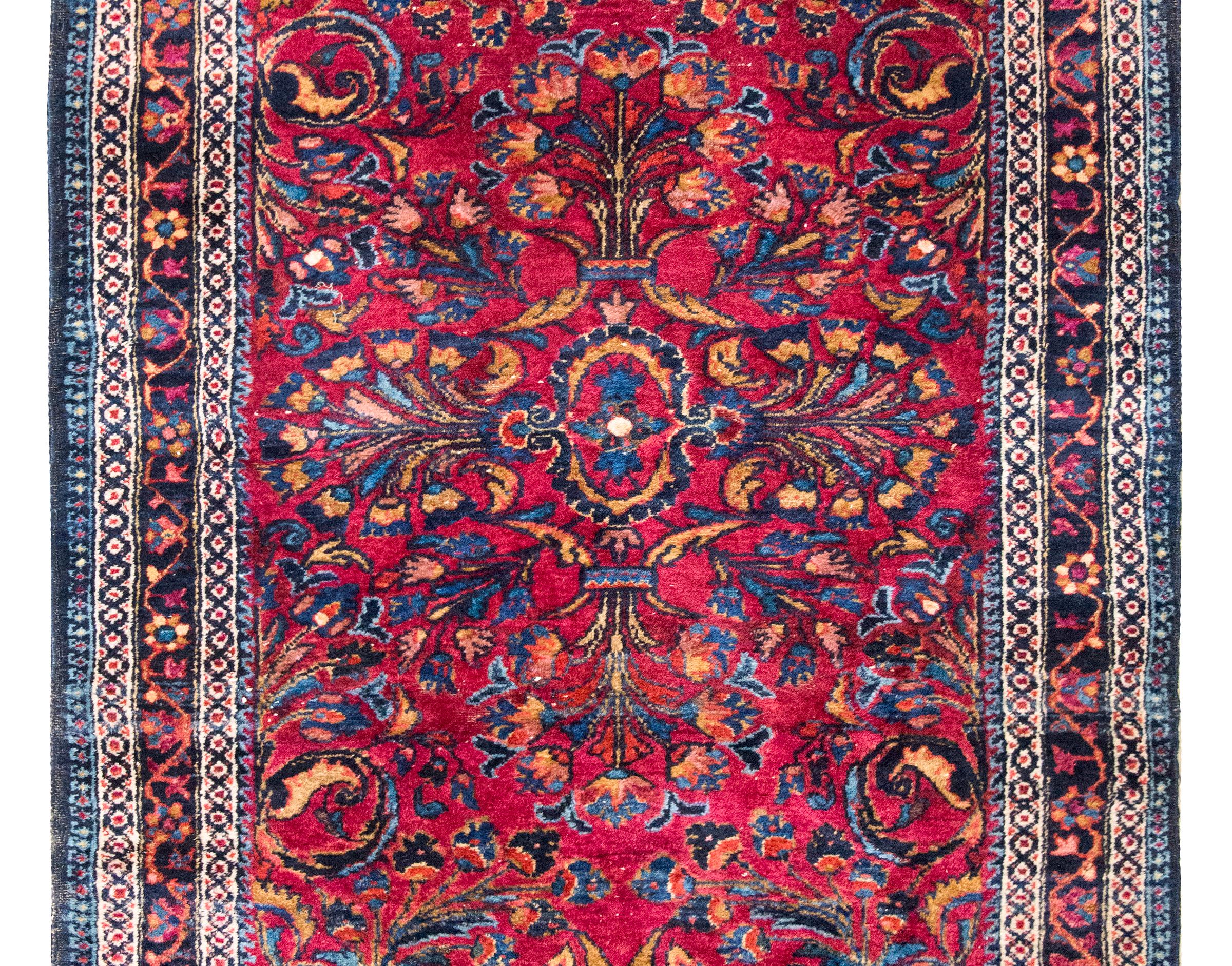 Tissé dans les années 1930, ce tapis persan Lilihan du début du XXe siècle est un exemple vibrant de l'artisanat villageois de l'ouest de l'Iran. Le champ central présente un motif floral en miroir - des fleurs stylisées, des vignes enroulées et des
