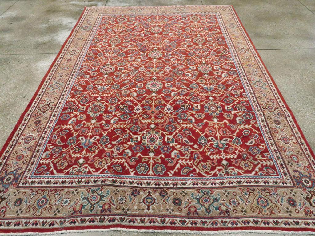 An antique Persian Mahal accent carpet. There are three vertical design axes with rosette bosses and angular undulating vines on the closely decorated warm madder red field of this Persian size Mahal. While we prefer eight by ten, the Persians go