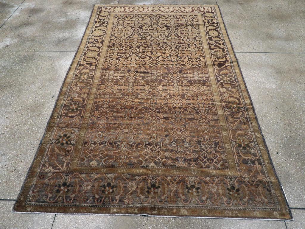 An antique Persian Mahal accent rug. Both the Herati allover field, and the rosette and tangerine flower side borders are abrashed in tones of slate to charcoal in this rustic west Persian long rug/narrow carpet. At the ends, the borders are