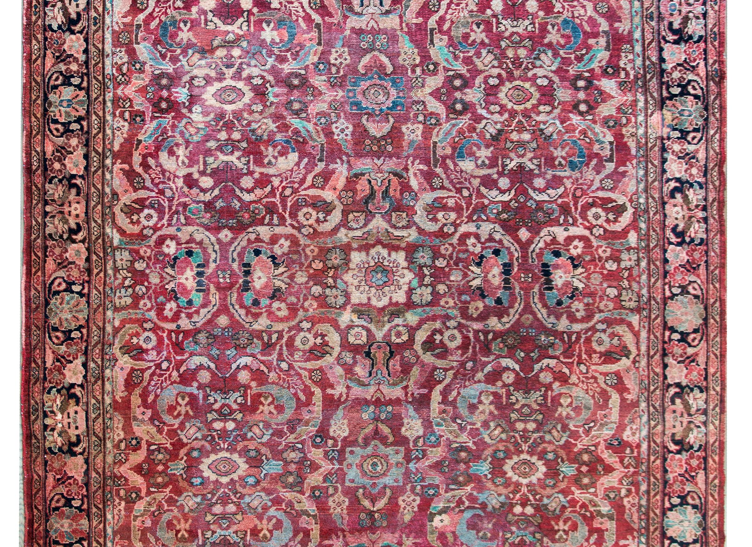 A gorgeous early 20th century Persian Mahal rug with the most incredible mirrored trellis floral pattern woven in cream, brown, pink, and indigo set against a cranberry background, and framed by a complex border with a wide central large-scale