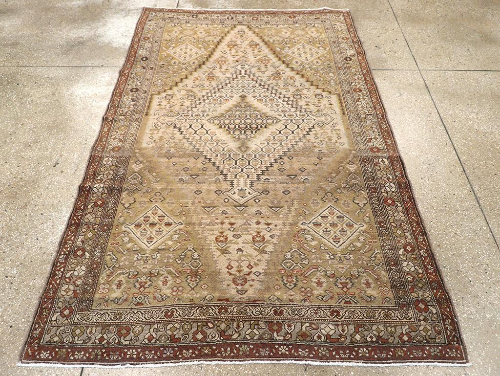 An antique Persian Malayer accent rug. Rust Herati corners frame a kilim design tall, light brown abrashed field featuring a nested kilim-style medallion. The blue-grey border has geometric flowers facing alternately left and right. This is a very