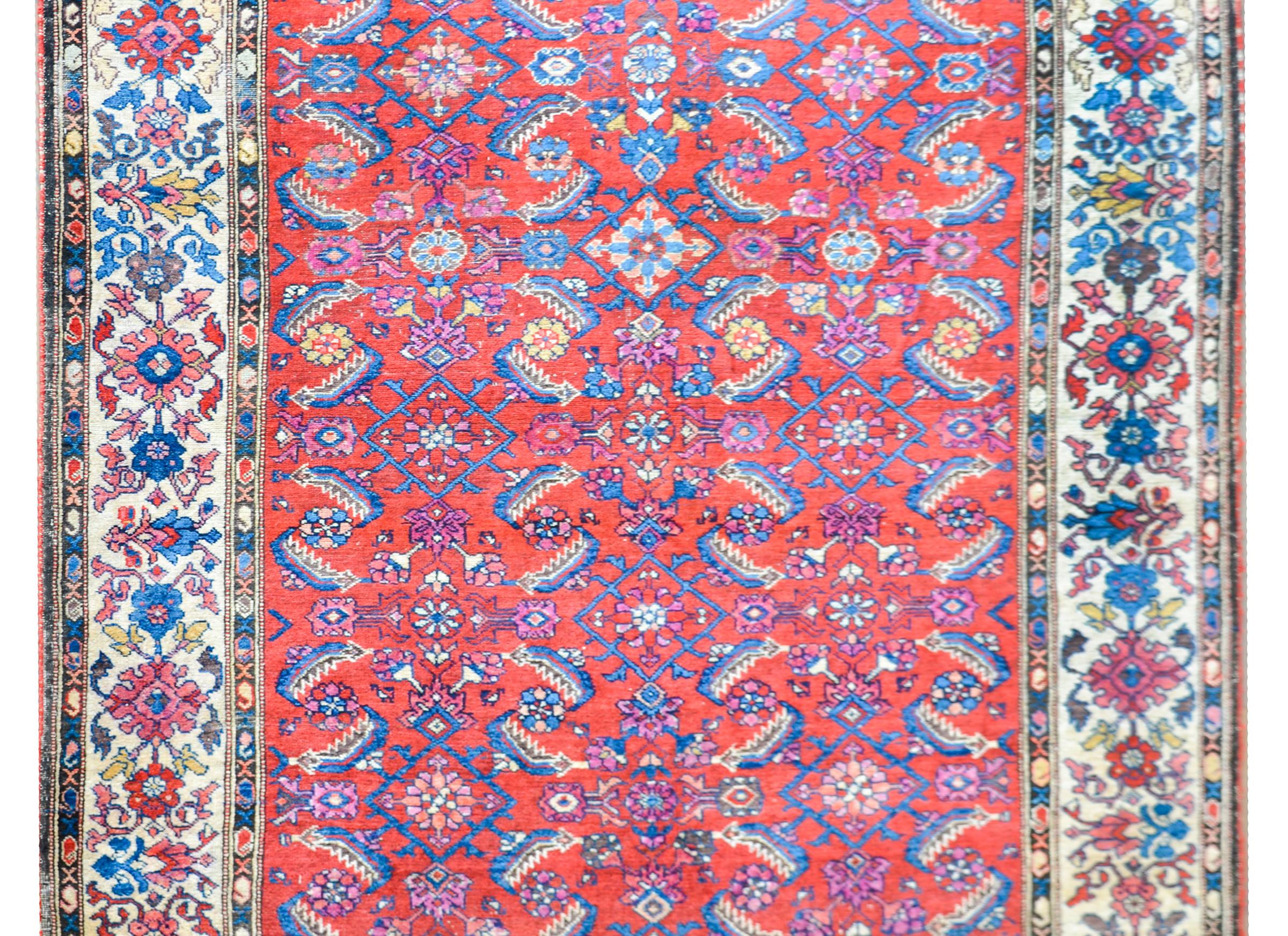 A beautiful early 20th century Persian Malayer rug with an allover trellis floral and leaf patterned field woven in pink, indigo, and cream, and set against a cimson background. The border is absolutely beautiful with several petite patterned