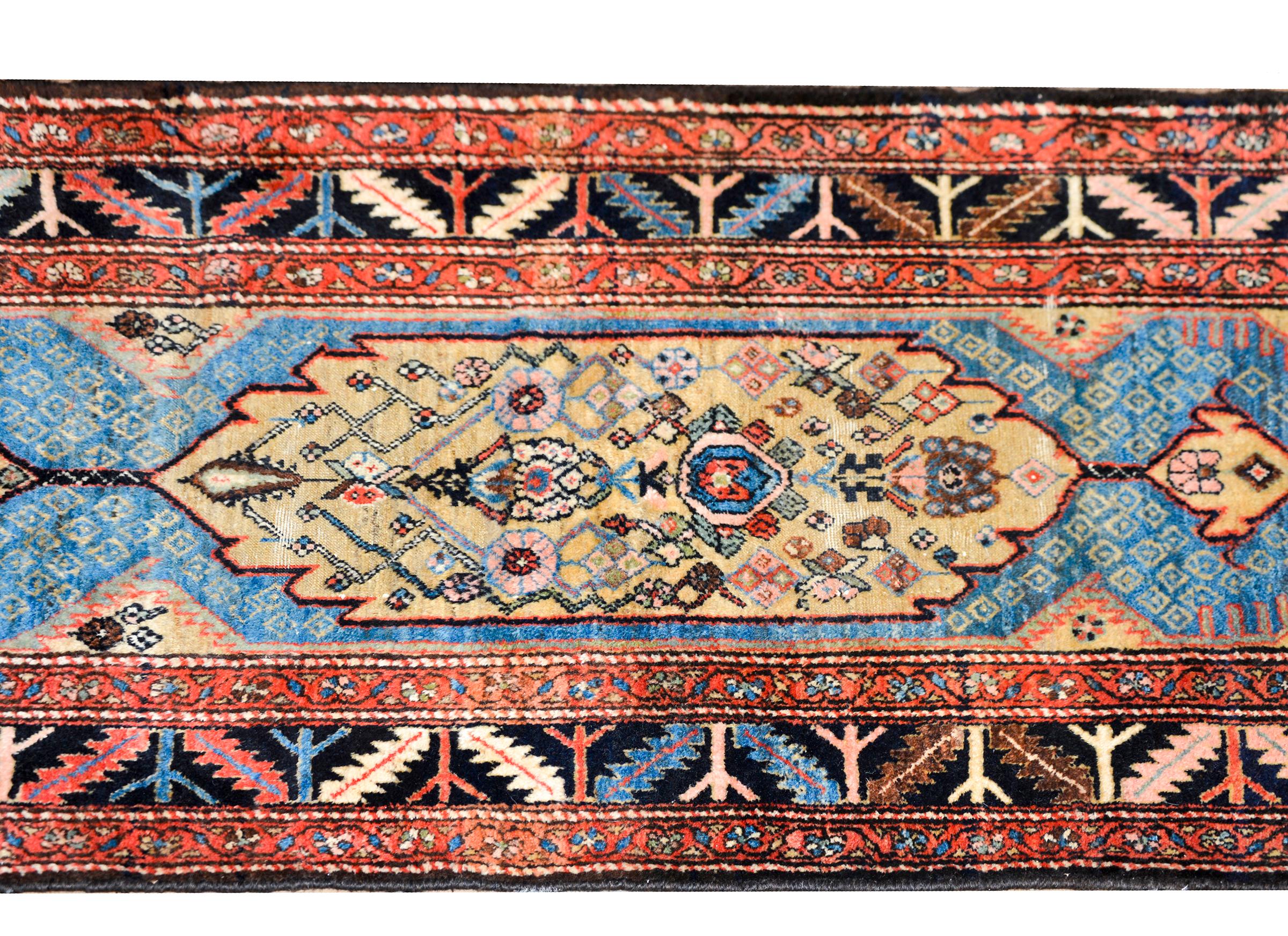 A stunning early 20th century Persian Malayer runner with multiple central medallions with stylized flowers amidst a field of more geometric stylized flowers, and surrounded by a border containing several petite floral patterned stripes.