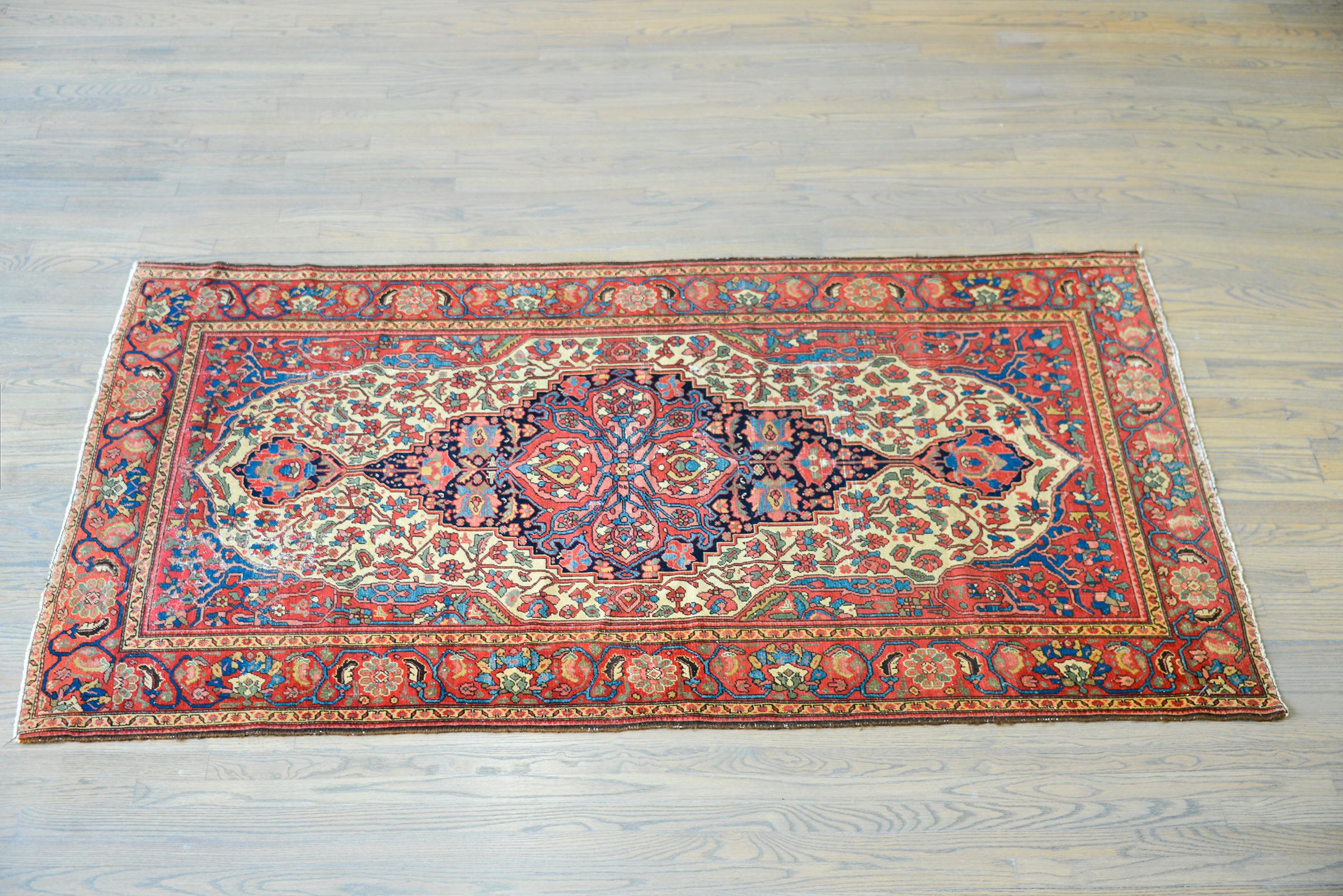 A gorgeous early 20th century Persian Malayer rug with a wonderful central floral medallion woven in brilliant reds, greens, golds, and indigos, set against a dark indigo background. The border is extraordinary with large-scale floral and scrolling