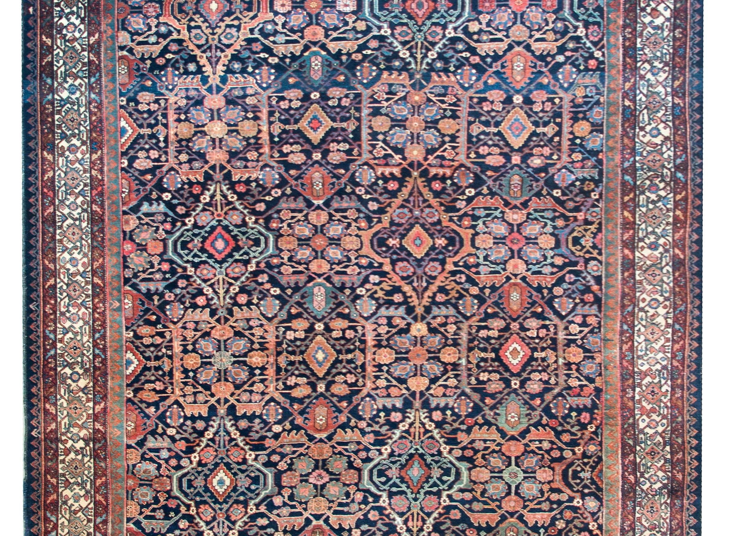 An incredible early 20th century Persian Malayer rug with an all-over lattice floral pattern woven in myriad colors including crimson, green, gold, light and dark indigo, and all set against a dark indigo background.  The border is complex with