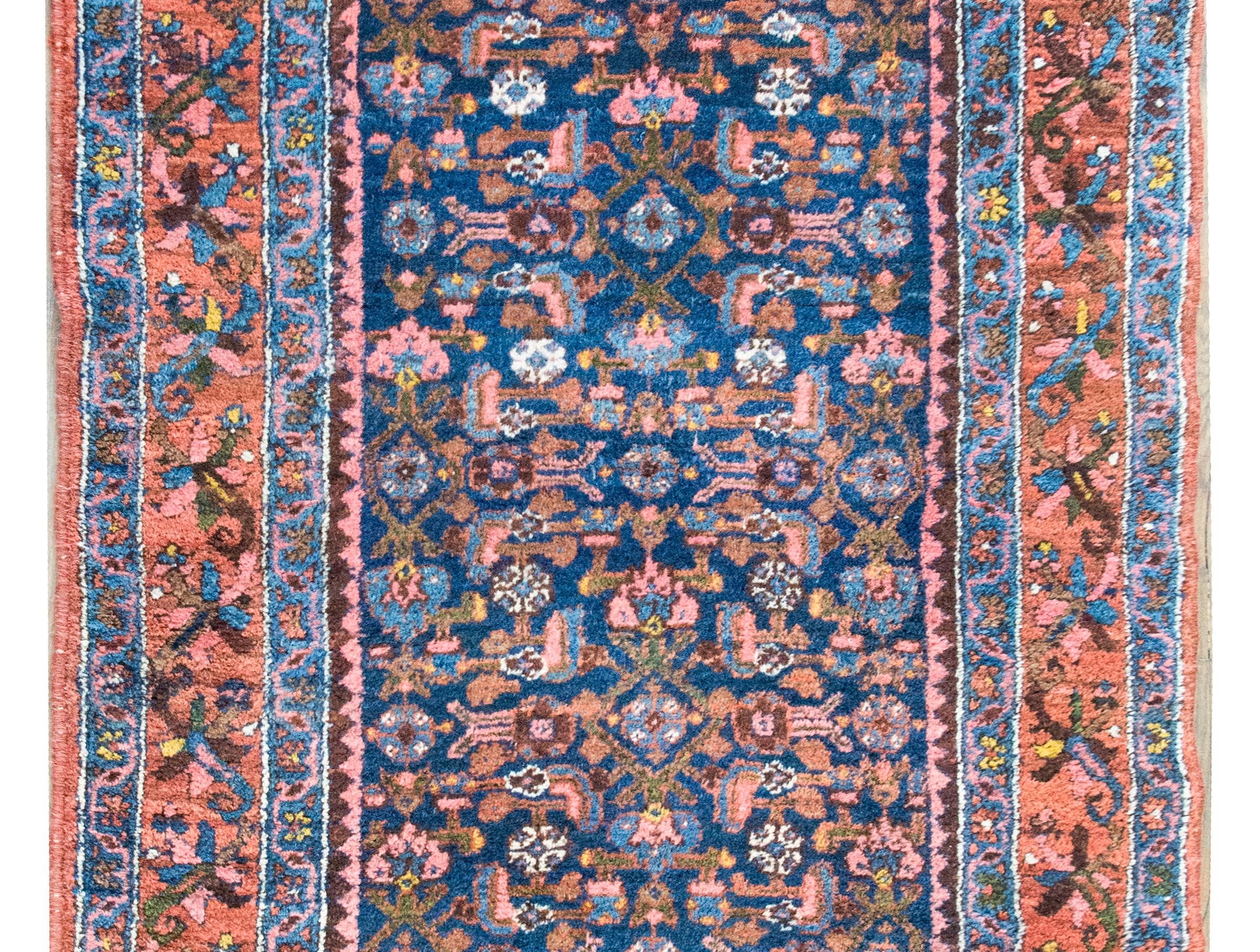Alfombra persa Malayer de principios del siglo XX, con un campo central con motivos florales y de hojas, rodeado de un complejo borde con una franja central floral y de enredaderas flanqueada por pares de pequeñas franjas florales y geométricas a