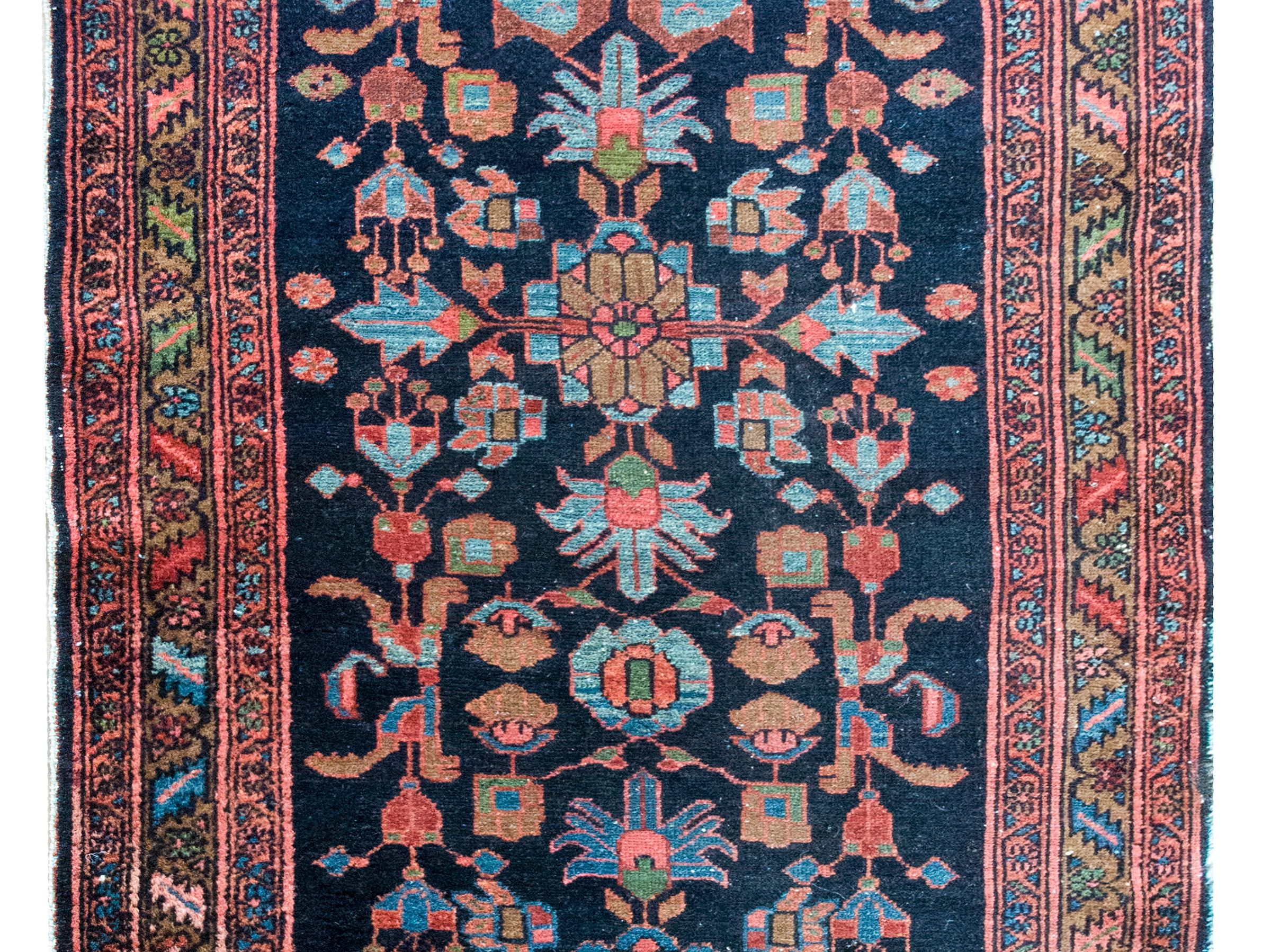 Un meraviglioso tappeto persiano Malayer dell'inizio del XX secolo con un audace motivo floreale stilizzato tessuto in una miriade di colori, tra cui cremisi scuro, indaco, marrone, verde e rosa, su uno sfondo indaco scuro.  Il bordo è complesso con