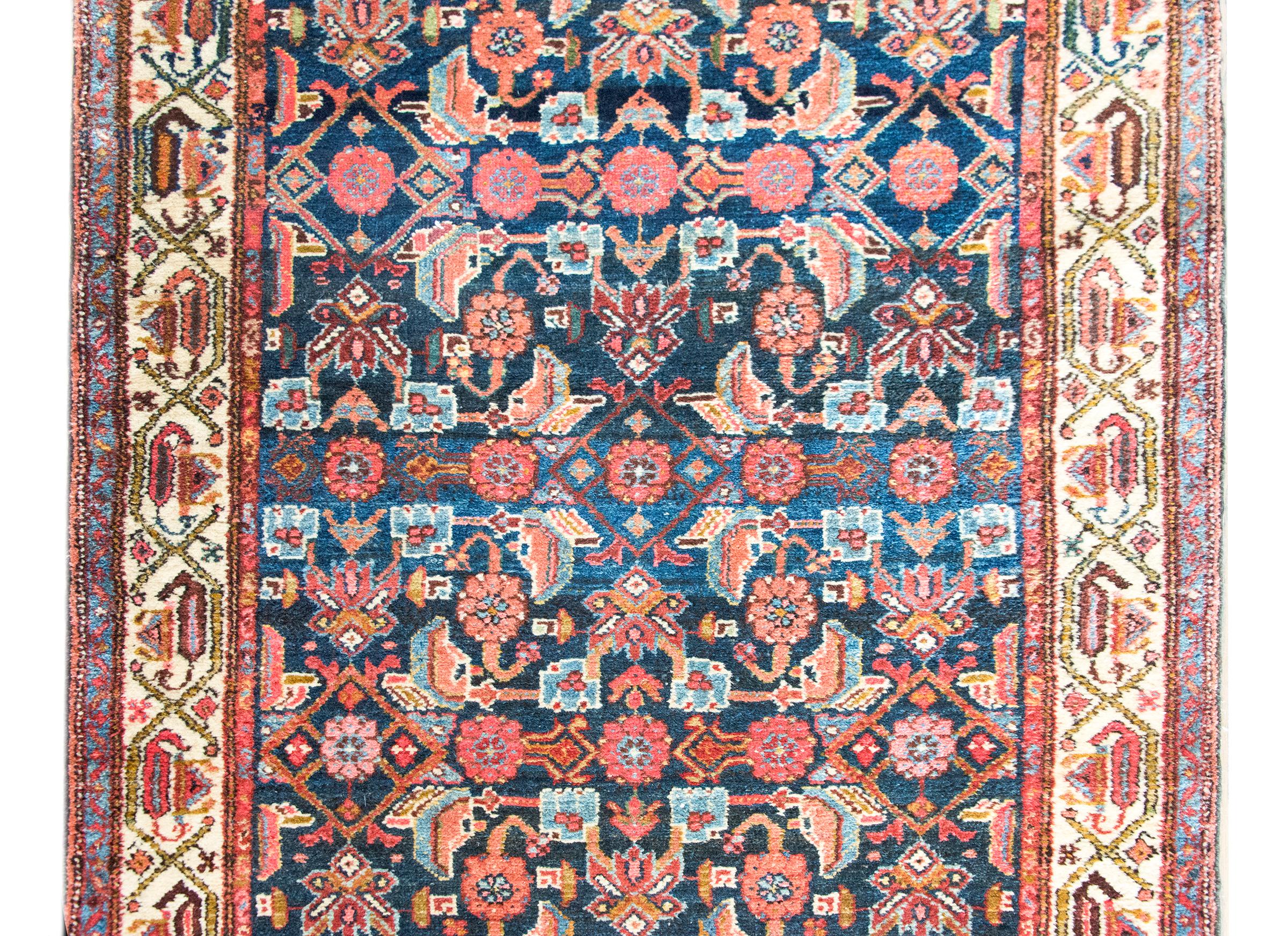 Alfombra persa Malayer de principios del siglo XX, con un diseño enrejado, tejida a mano en una lírica mezcla de carmesí, rosa, crema, marrón suave y toda una gama de índigos. El diseño presenta un entramado rítmico de flores a gran escala y hojas