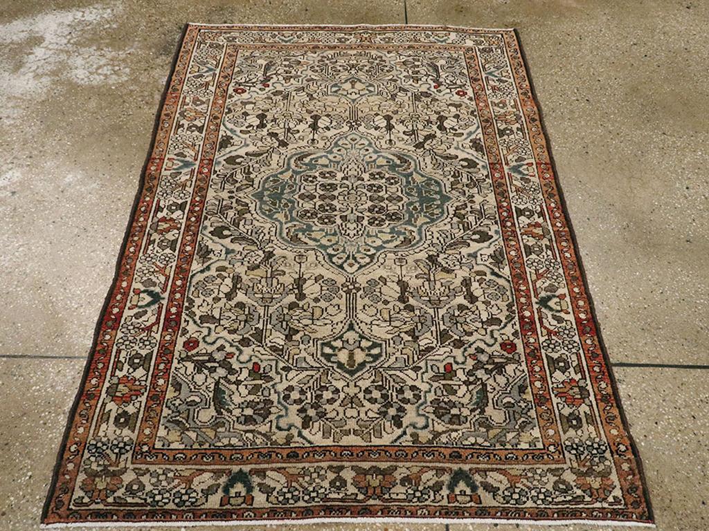 Una alfombra persa Malayer vintage. Un medallón gris pizarra suavemente festoneado con colgantes alargados tiene un centro de roseta marfil y está colocado sobre un campo beige claro estrechamente lleno de zarcillos florales. El borde principal