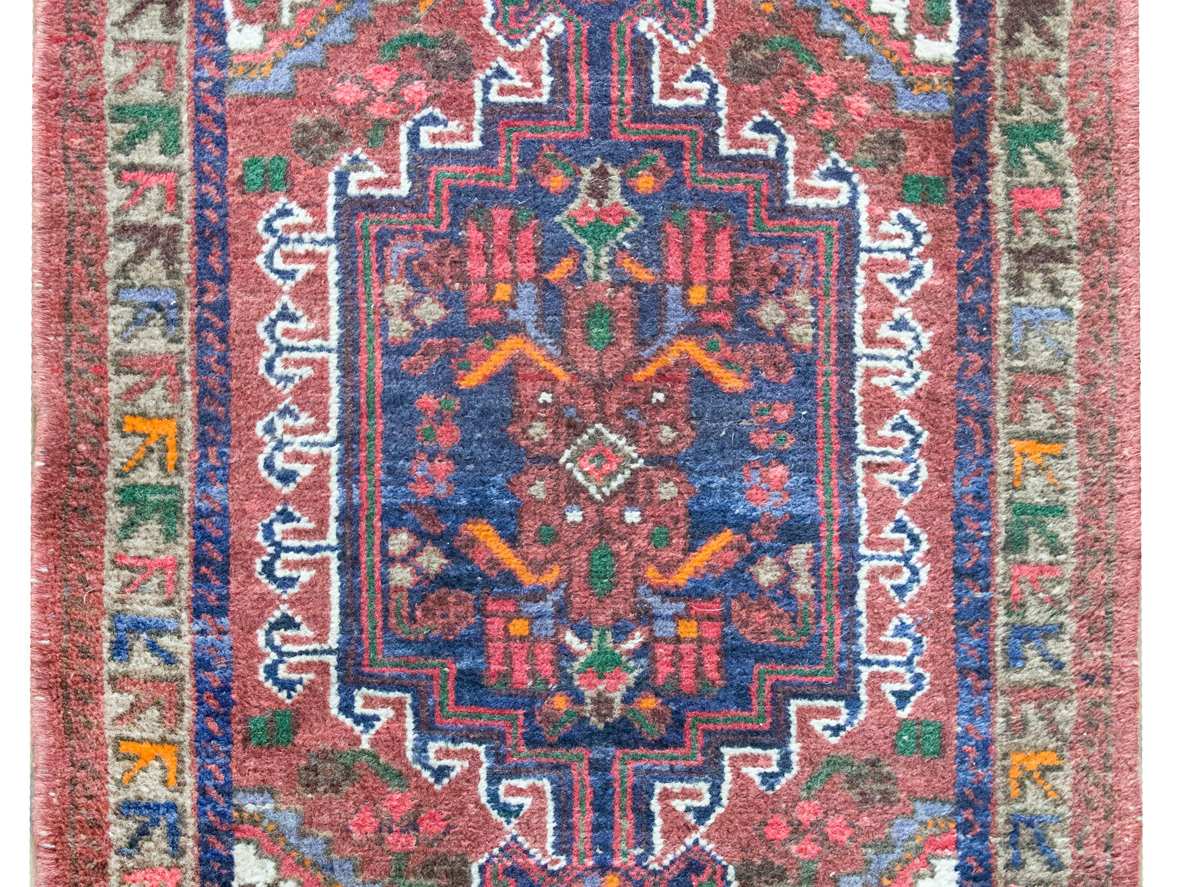 Un bellissimo tappeto persiano Mazlaghan dell'inizio del XX secolo con un motivo tribale contenente fiori stilizzati e viti che scorrono, che vivono in un campo di altri fiori, il tutto circondato da un semplice bordo con fiori ancora più