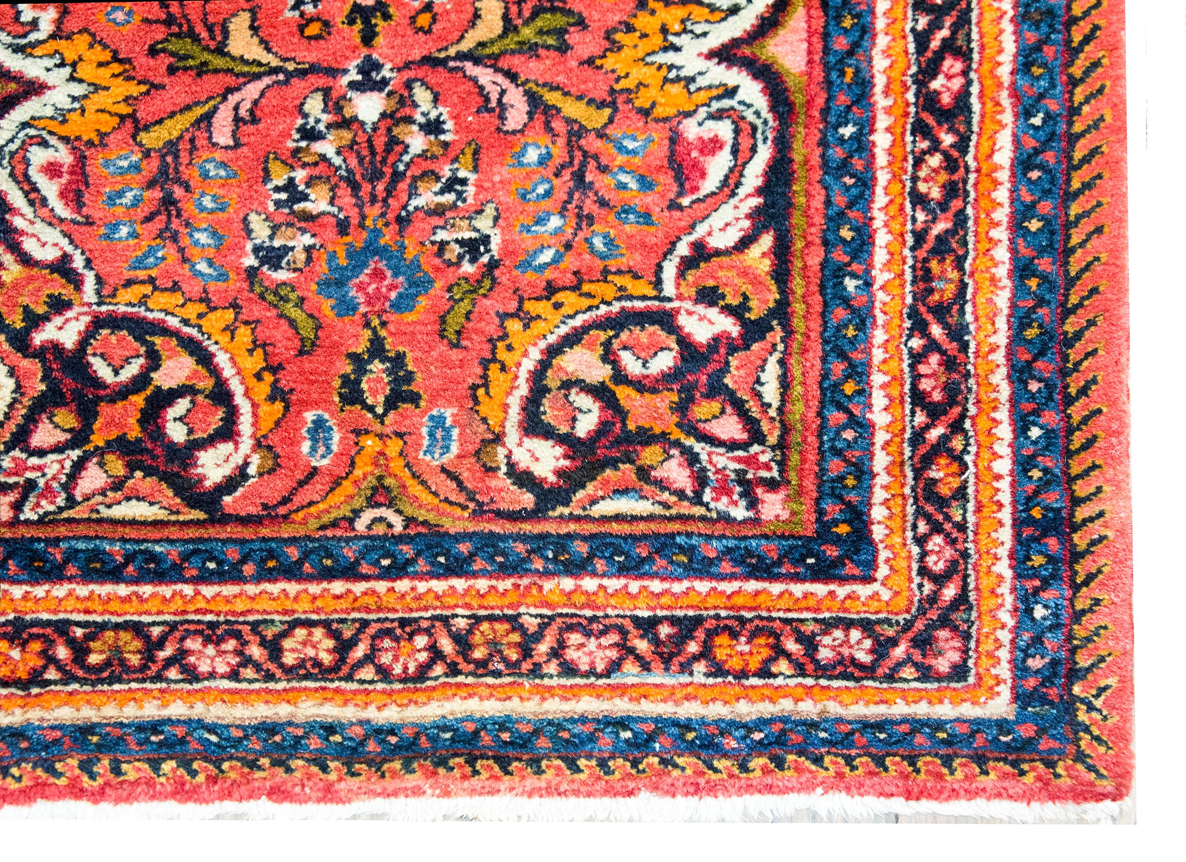 This early 20th-century Persian Mehraban rug is a radiant expression of village weaving tradition from northwestern Iran. At its center lies a large floral medallion, its stylized petals and leafy tendrils blossoming amidst a vibrant field teeming