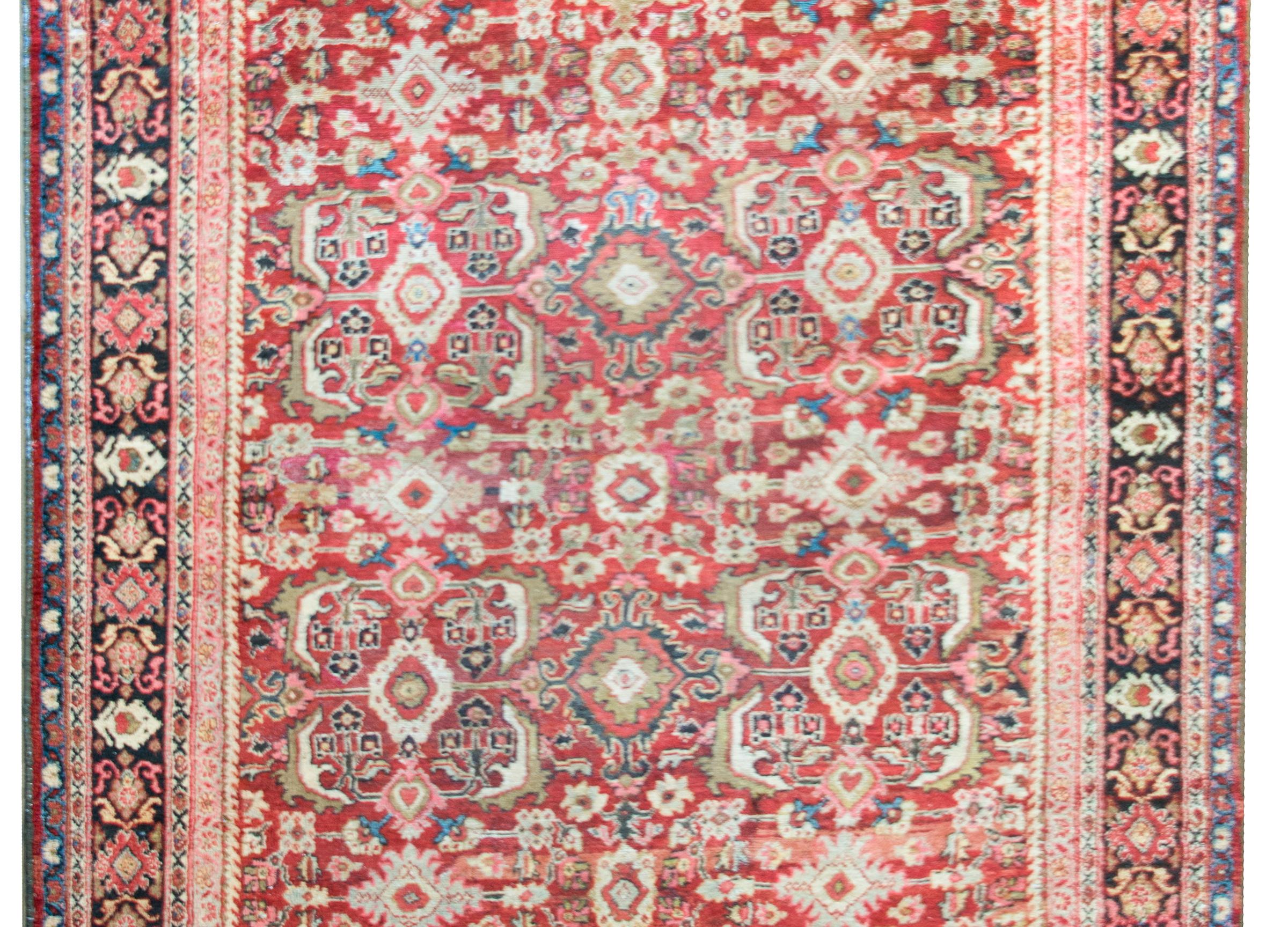 A stunning early 20th century Persian Meshkabad rug with an all-over floral pattern containing myriad large-scale flowers, leaves, and scrolling vines, and all surrounded by several floral patterned striped.