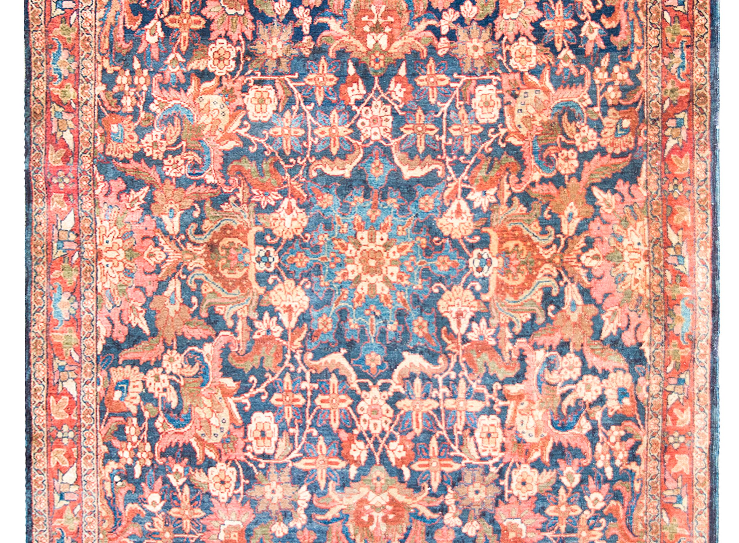 Superbe tapis persan Meshkabad du début du 20e siècle présentant un incroyable motif avec un grand médaillon floral central vivant au milieu d'un champ de fleurs densément tissées et de vignes enroulées, et entouré d'une bordure complexe avec une