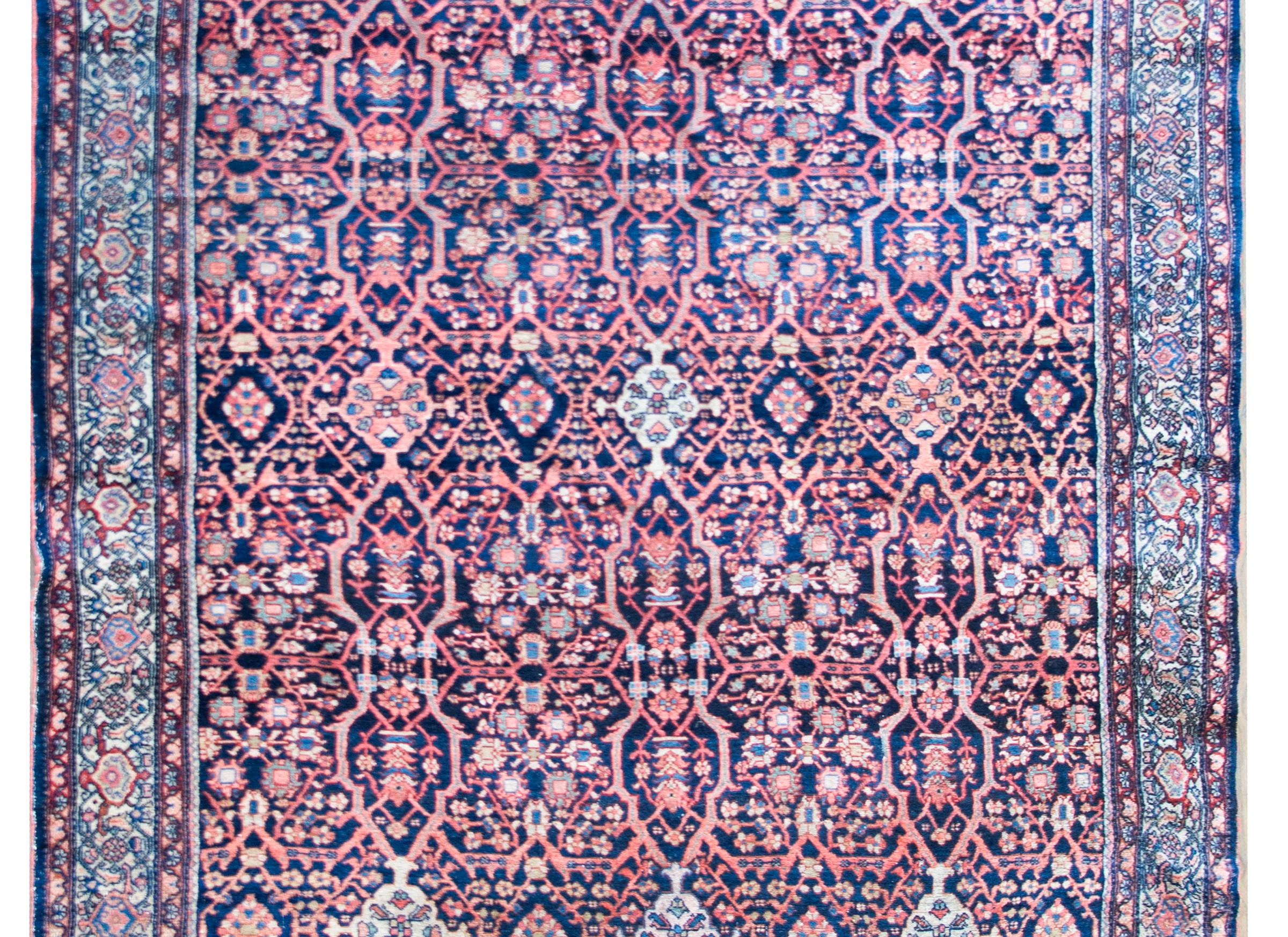 A fantastic early 20th century Persian Mission Malayer rug with an all-over floral trellis pattern containing myriad flowers woven in various colors including light and dark indigo, pink, green, cream, and crimson, and surrounded by a wonderful