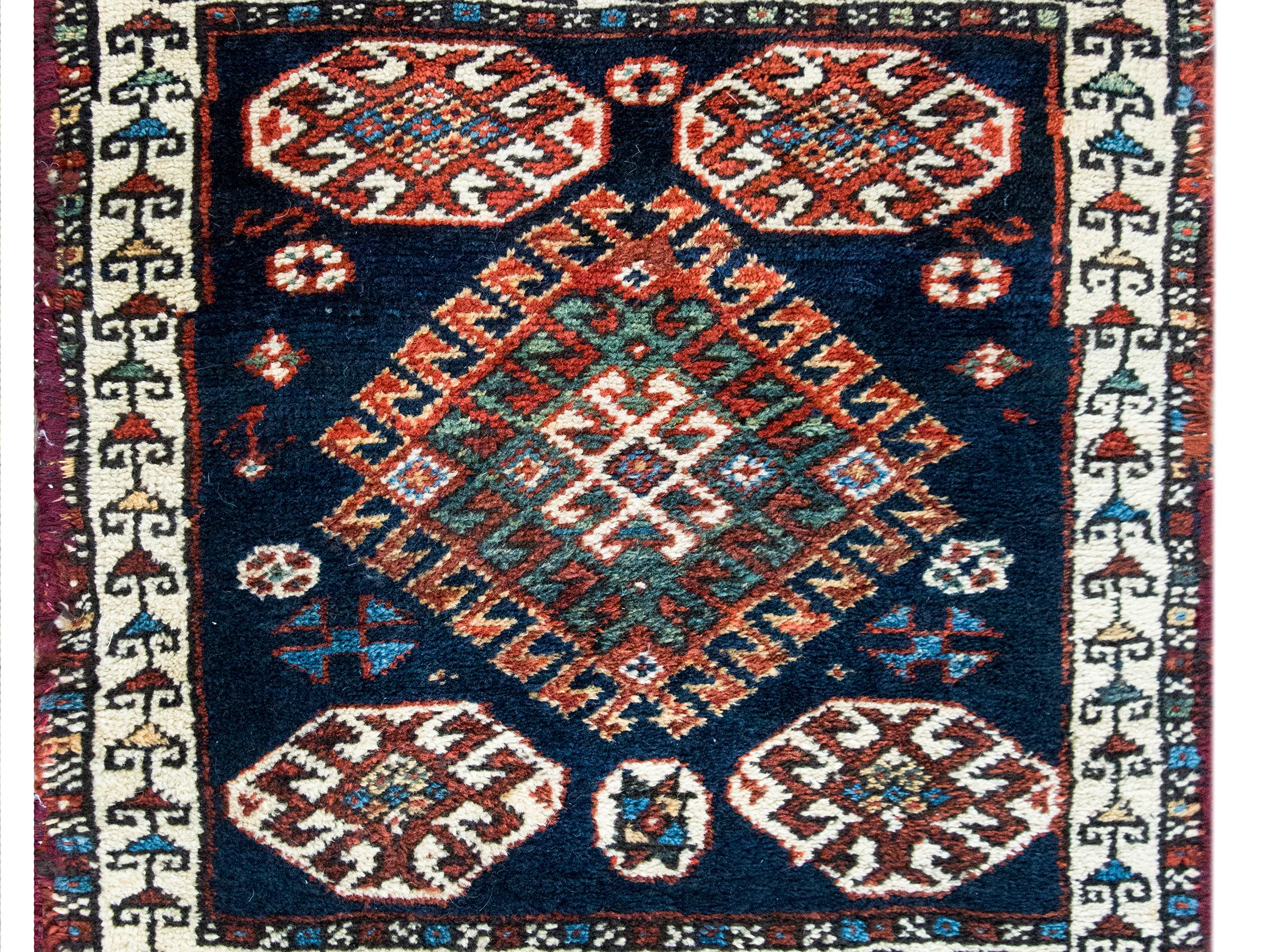 Un bellissimo tappeto persiano Qashqai dell'inizio del XX secolo con un medaglione floreale centrale stilizzato in mezzo a un campo di fiori ancora più stilizzati e circondato da un semplice bordo con piccole viti e fiori a scorrimento, il tutto