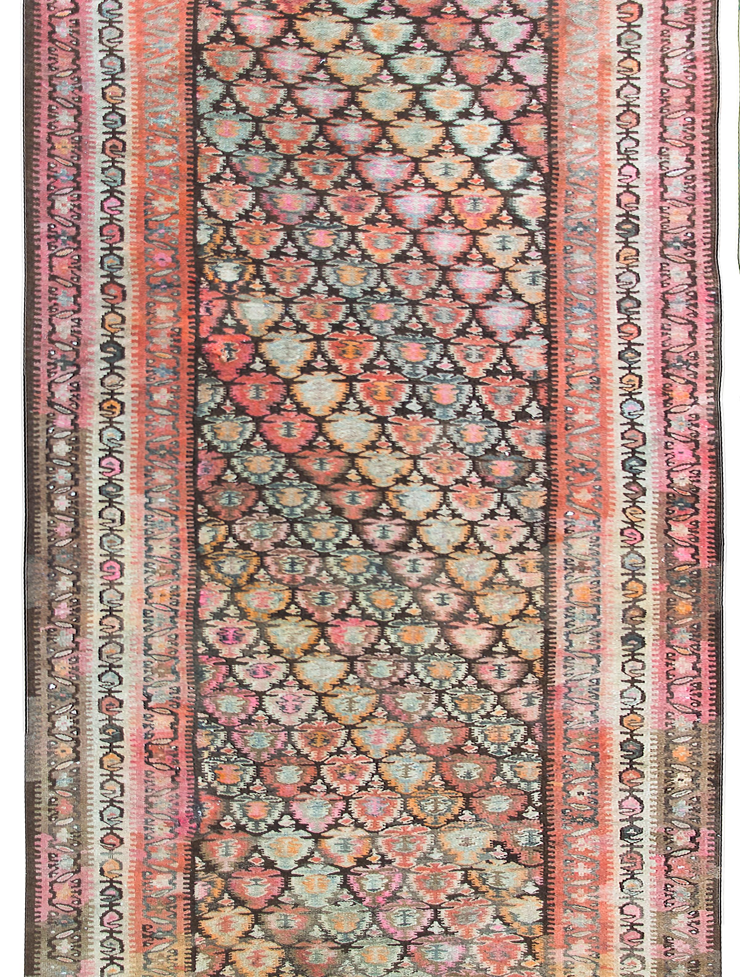 Un incroyable et saisissant tapis persan Rug & Kilim du début du 20e siècle avec un motif floral tissé en bandes diagonales colorées, entouré de petits motifs floraux complexes, le tout tissé dans des tons corail, or, rose, marron et gris.  