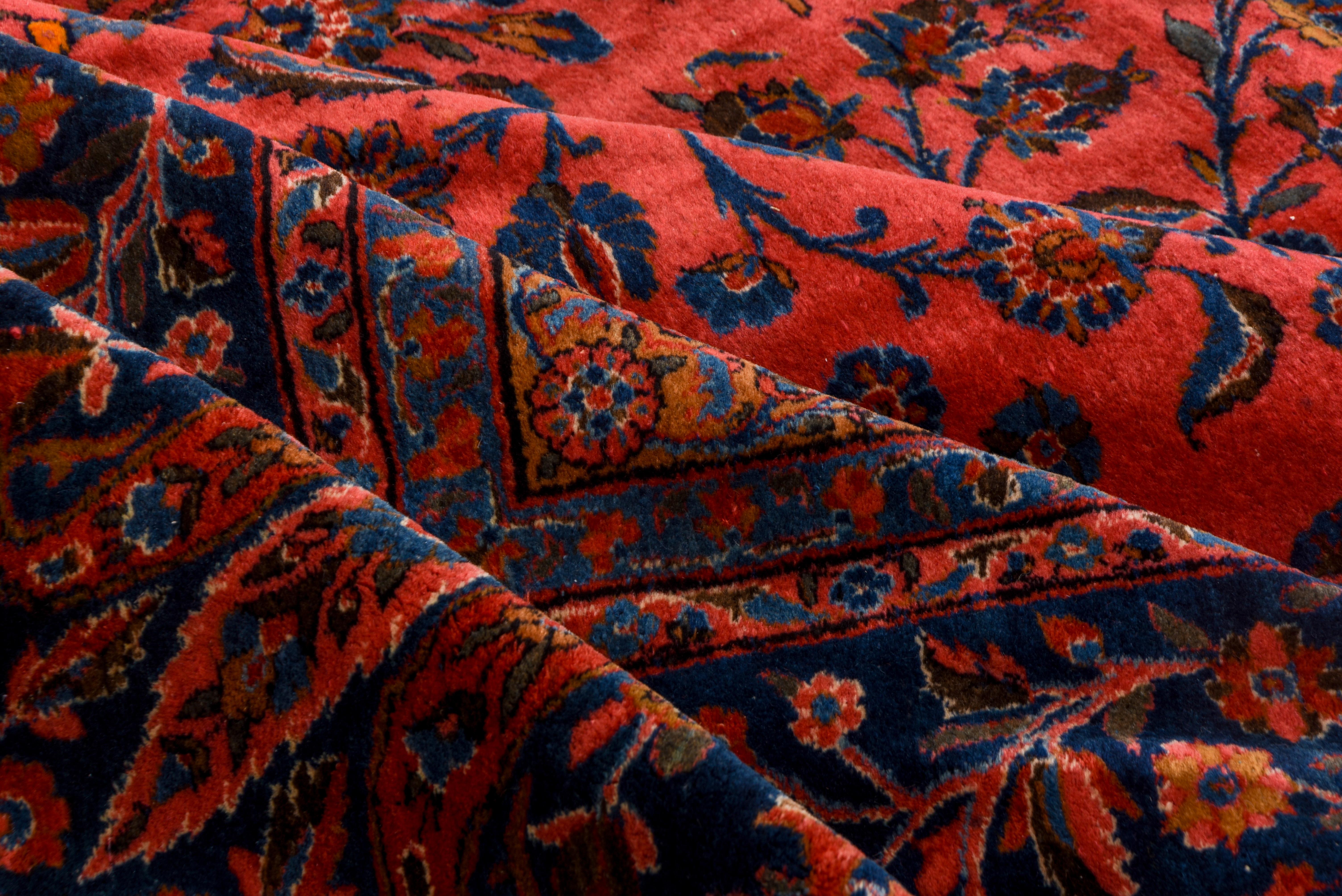 The scarlet field of luxurious English spun wool features a floating floral spray pattern derived from contemporaneous 