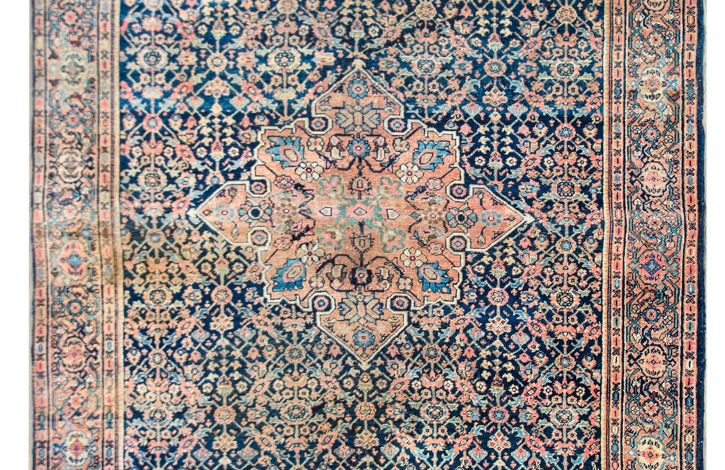 An incredible early 20th century Persian Sarouk Farahan rug with a large central floral medallion living in a trellised field of more flowers and surrounded by a complex border of even more stylized flowers and pomegranates, all woven in wonderful
