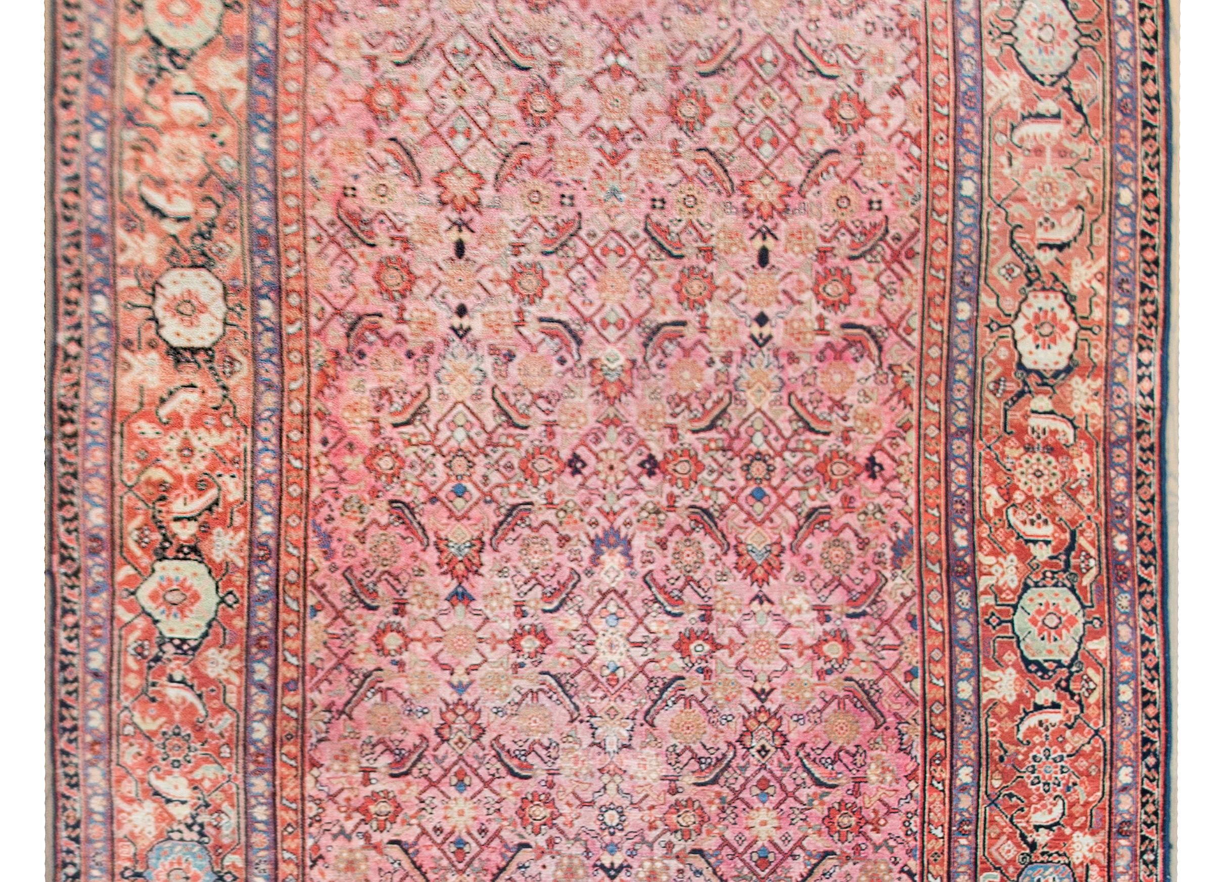 A remarkable late 19th century Persian Sarouk Farahan rug with the most incredible all-over trellis pattern with myriad paisleys, flowers, and scrolling vines, all woven in coral, pink, gold, and indigo. The border is extraordinary with large-scale