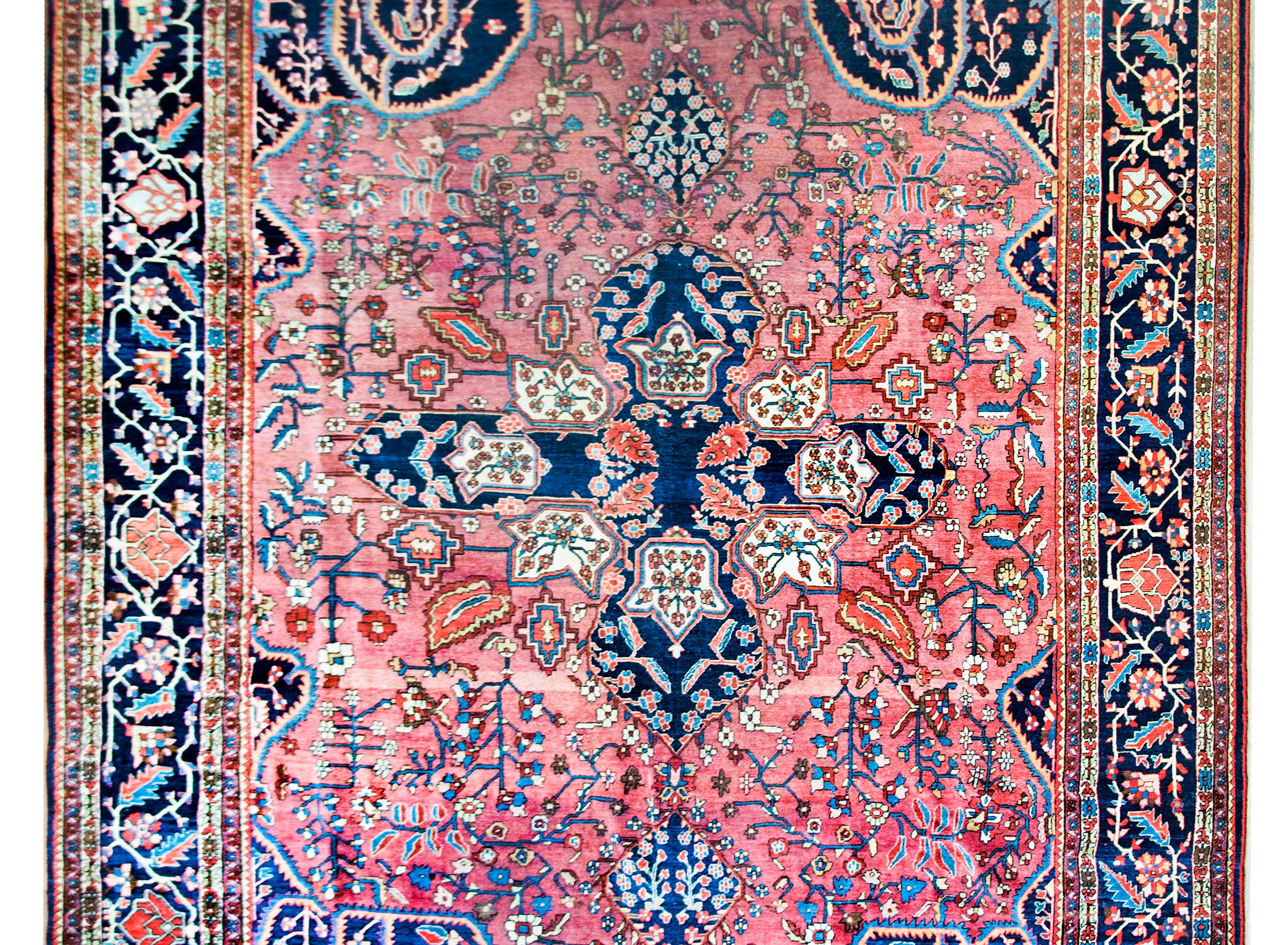 A remarkable early 20th century Persian Sarouk Farahan rug with the most memorable pattern we've seen in a long time. A large indigo cross-form medallion lives in the center of stylized scrolling vines and flowers with large spiral scrolled vines in