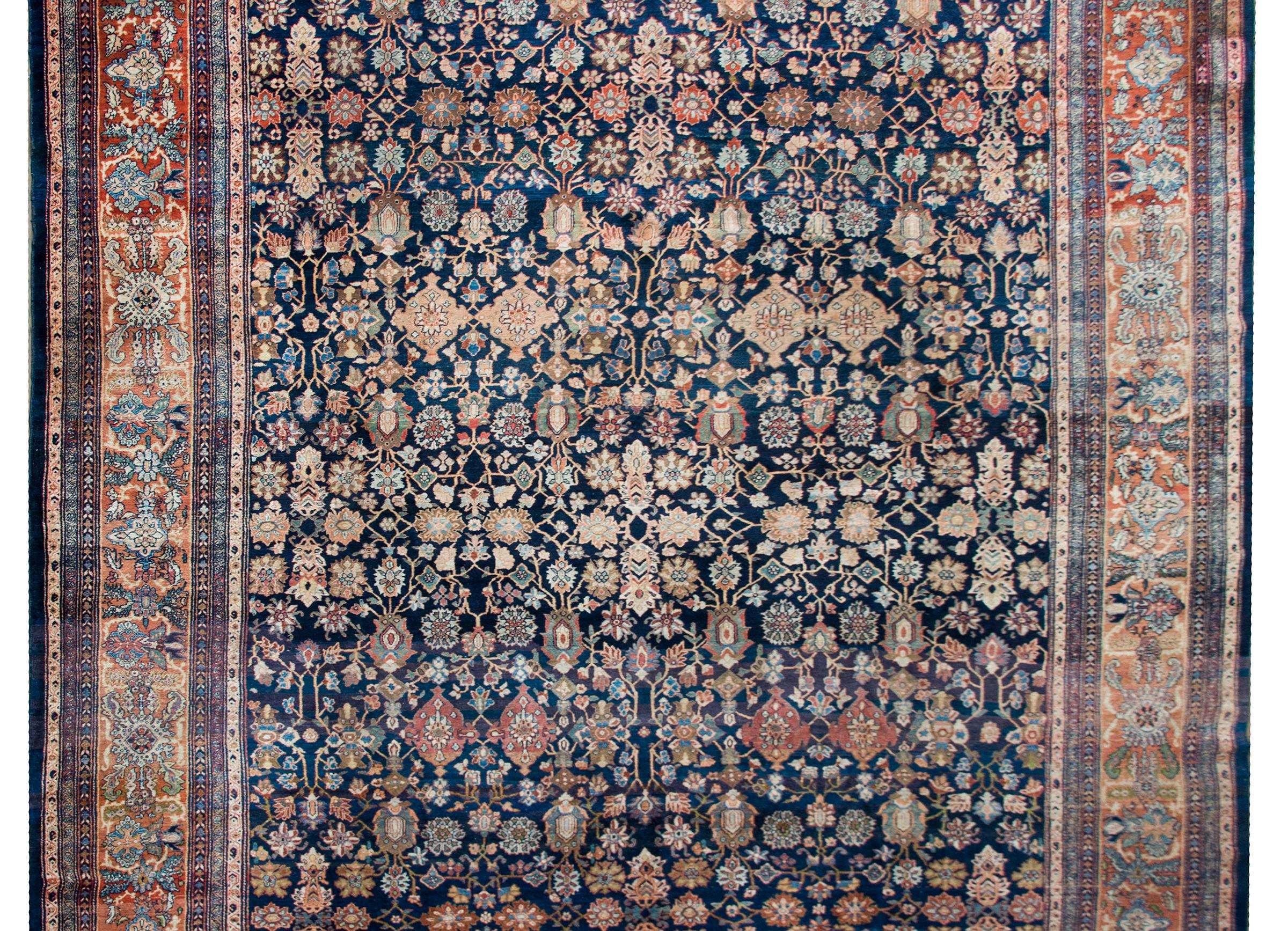 A remarkable early 20th century Persian Sarouk Farahan rug the most wonderful all-over repeated pattern woven with myriad stylized flowers and scrolling vines, and all woven in light and dark indigo, cream, coral, green, and white wool. The border