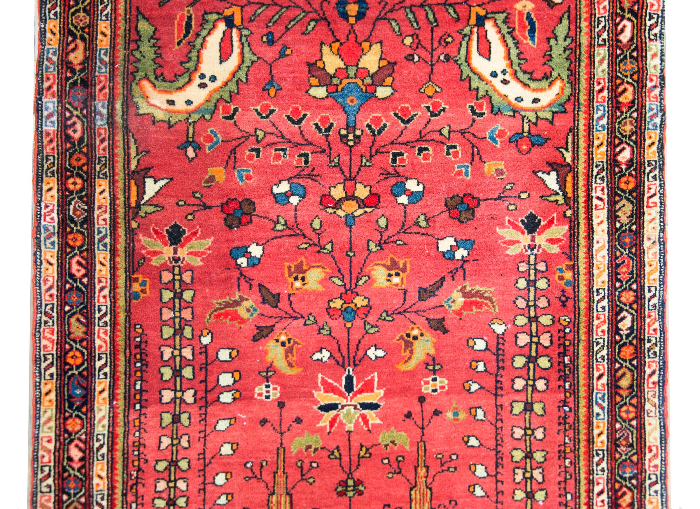 A wonderful early 20th century Persian Sarouk Farahan rug with a traditional central tree-of-life motif flanked by pairs of more flowers and trees, and surrounded by an incredible border composed of several petite scales paisley and floral patterned
