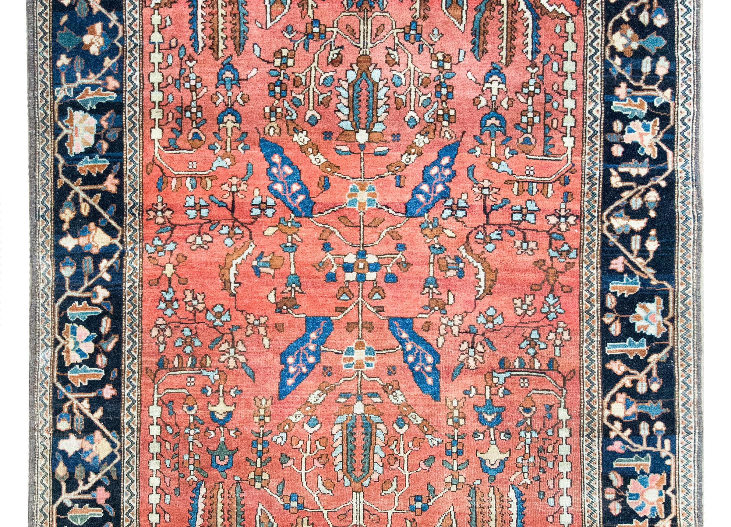 Uno splendido tappeto persiano Sarouk Farahan dell'inizio del XX secolo con un elegante motivo floreale e di viti a specchio su un fondo arancione, circondato da un bordo floreale stilizzato e da viti a scorrimento, il tutto tessuto in varie