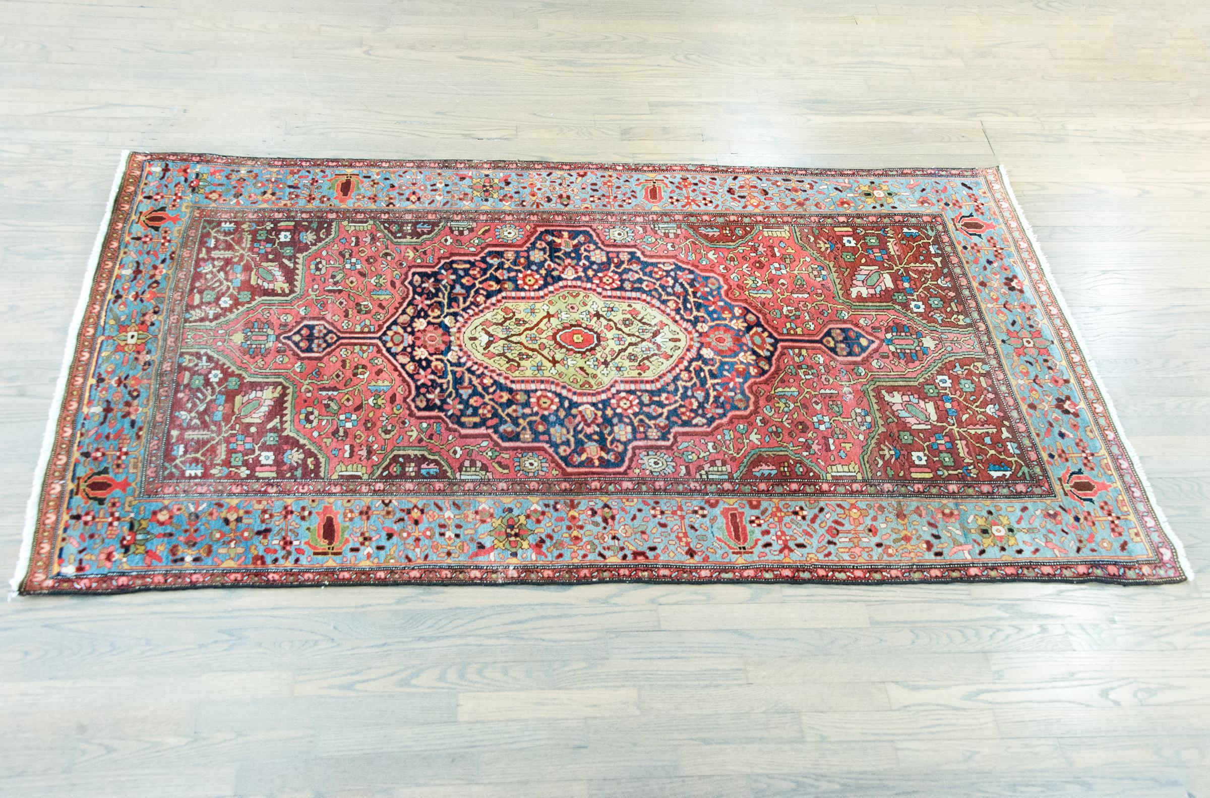 Un bellissimo e raro tappeto persiano Sarouk Farahan dell'inizio del XX secolo con un grande medaglione centrale con una miriade di fiori e tralci che si intrecciano in un arcobaleno di colori tra cui cremisi, rosa, giallo, oro, varie tonalità di