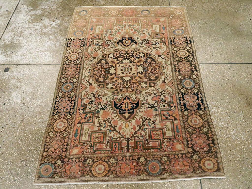 Ein antiker persischer Sarouk-Farahan-Teppich. Abgestufte Ecken rahmen das anthrazitfarbene Medaillon mit seinem dichten Palmetten- und Blattmuster ein. Das elfenbeinfarbene Feld weist an beiden Enden lange, Y-förmige Blütenbäume auf. Die