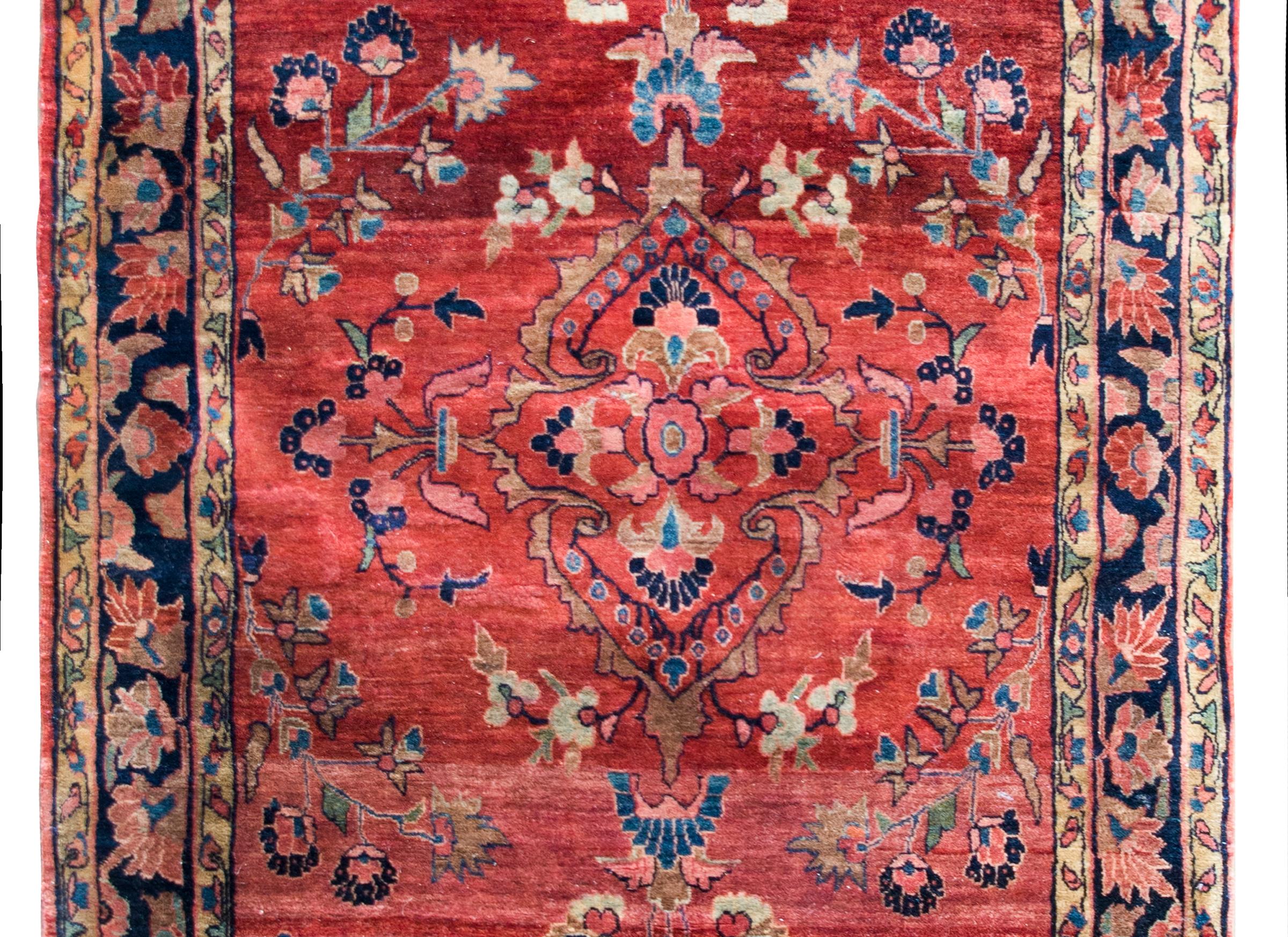 Uno splendido tappeto persiano Sarouk Mohajeran dell'inizio del XX secolo con un grande medaglione centrale floreale stilizzato in mezzo a un numero ancora maggiore di fiori, circondato da un semplice bordo con un'ampia striscia centrale a motivi