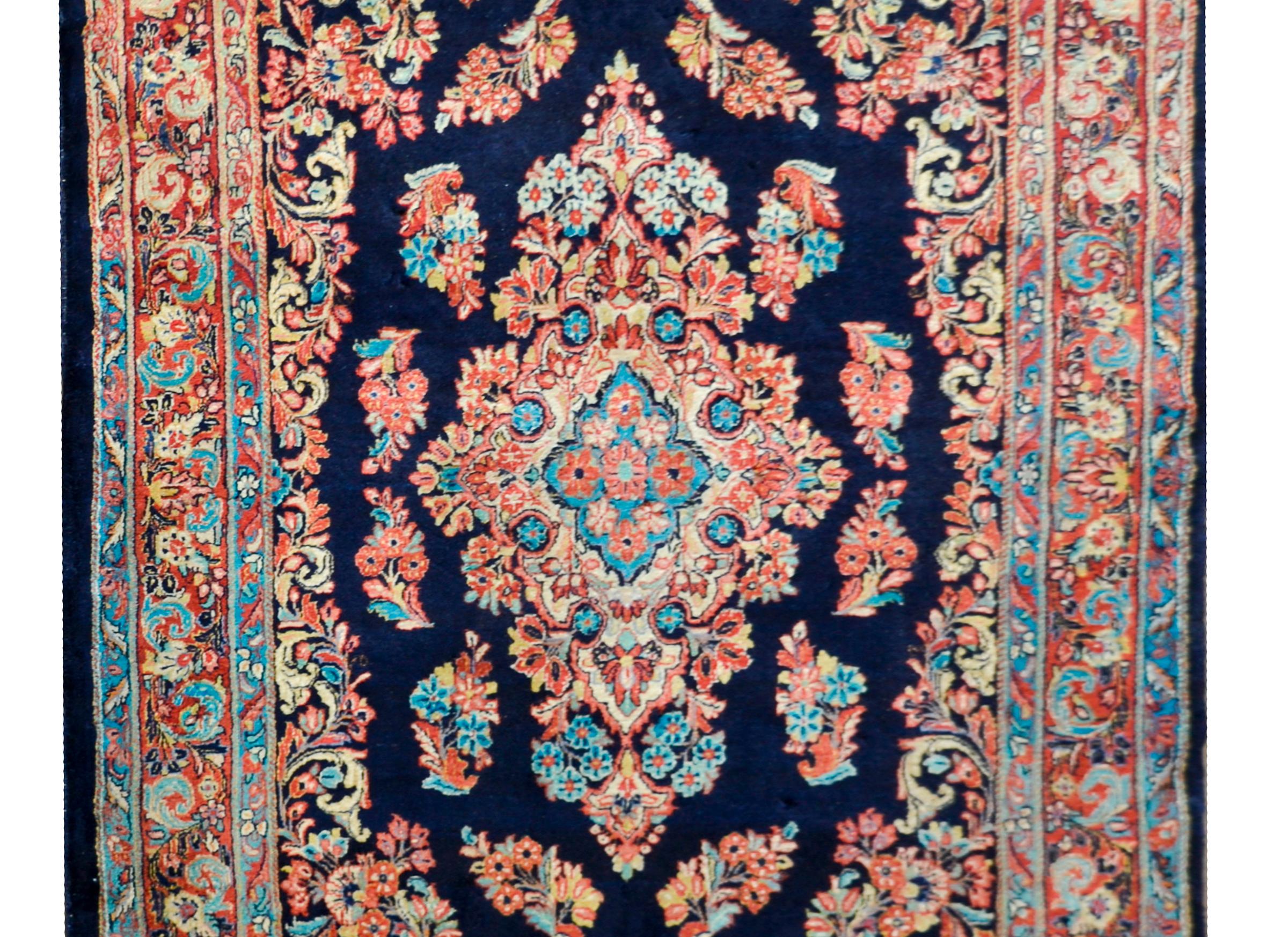 Un meraviglioso tappeto Sarouk persiano dell'inizio del XX secolo con un medaglione floreale centrale circondato da un bordo intrecciato con fiori simili e il centro. Il bordo è complementare con fiori e colori simili a quelli del campo.