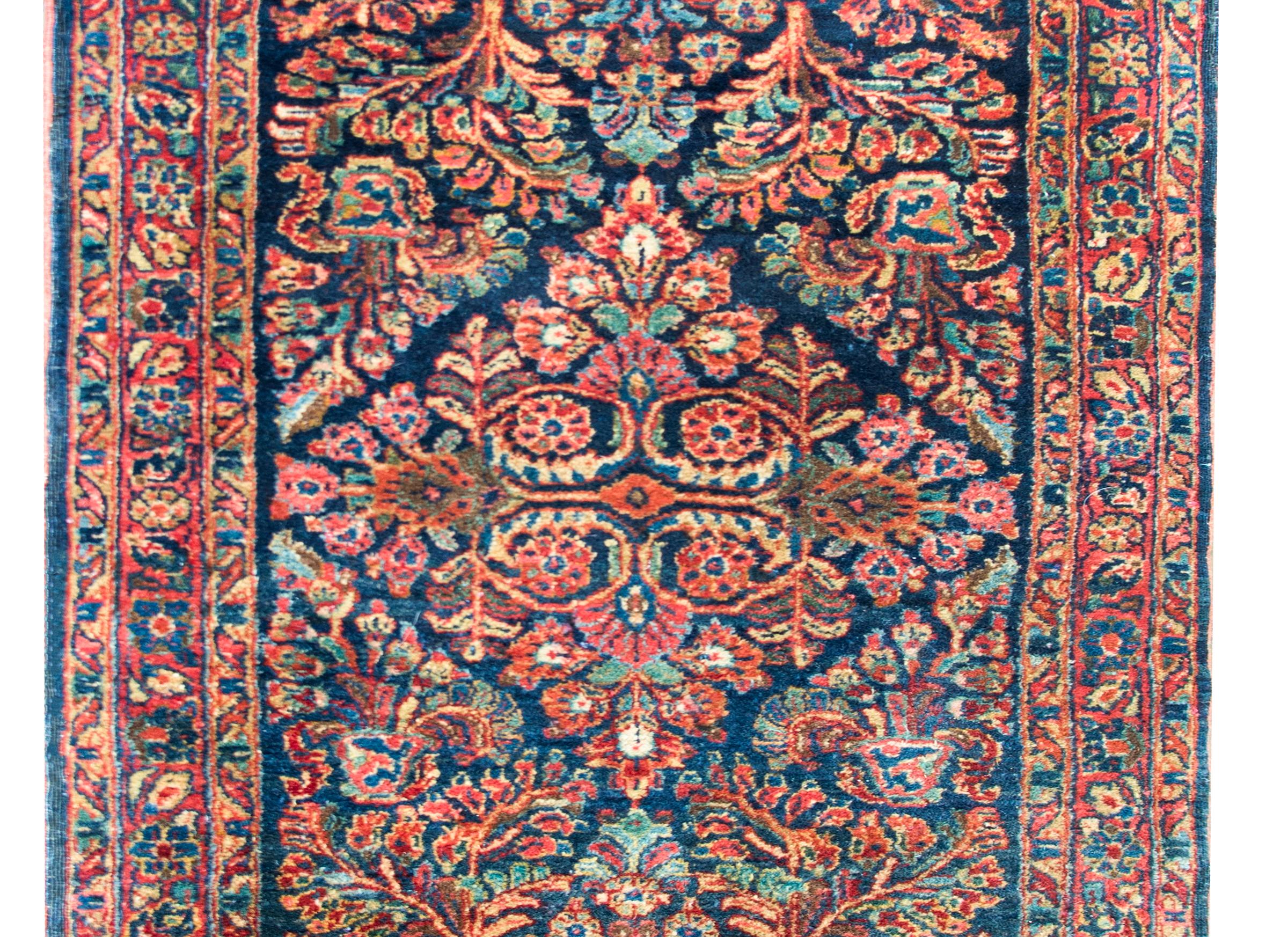 A gorgeous early 20th century Persian Sarouk rug with a large diamond floral medallion living admits a field of more flowers and leaves, and surrounded by a complex border of even more flowers and leaves, and all woven in traditional Sarouk colors
