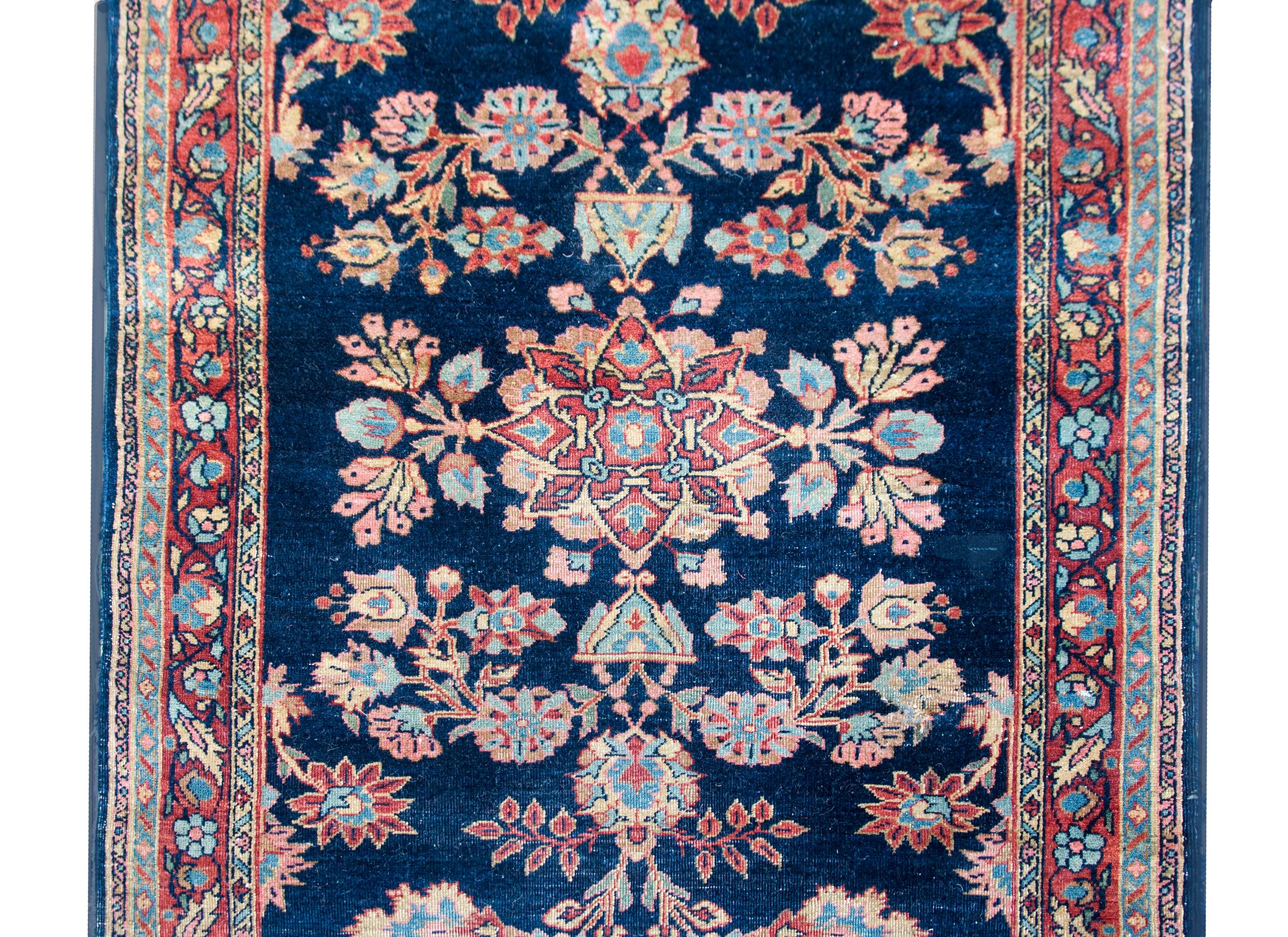 Uno splendido tappeto Sarouk persiano dell'inizio del XX secolo con un medaglione centrale circondato da un motivo floreale a specchio con una miriade di fiori, circondato da un bordo sottile con altri fiori e tutto tessuto in varie tonalità di lana