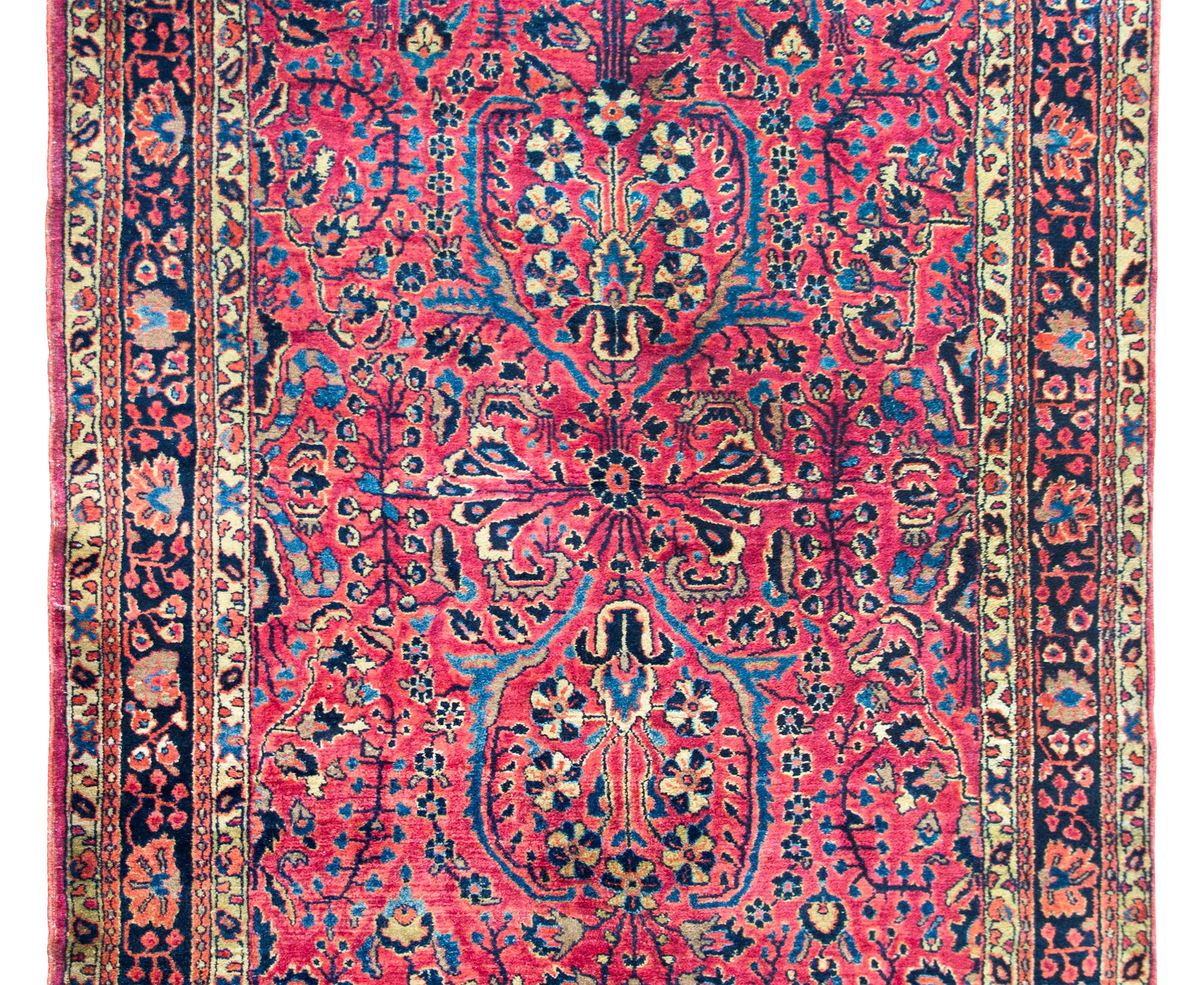 Un bellissimo tappeto Sarouk persiano dell'inizio del XX secolo con un motivo floreale a specchio con una miriade di fiori stilizzati e tralci che scorrono, circondato da un bordo con una striscia centrale a motivi floreali affiancata da coppie di