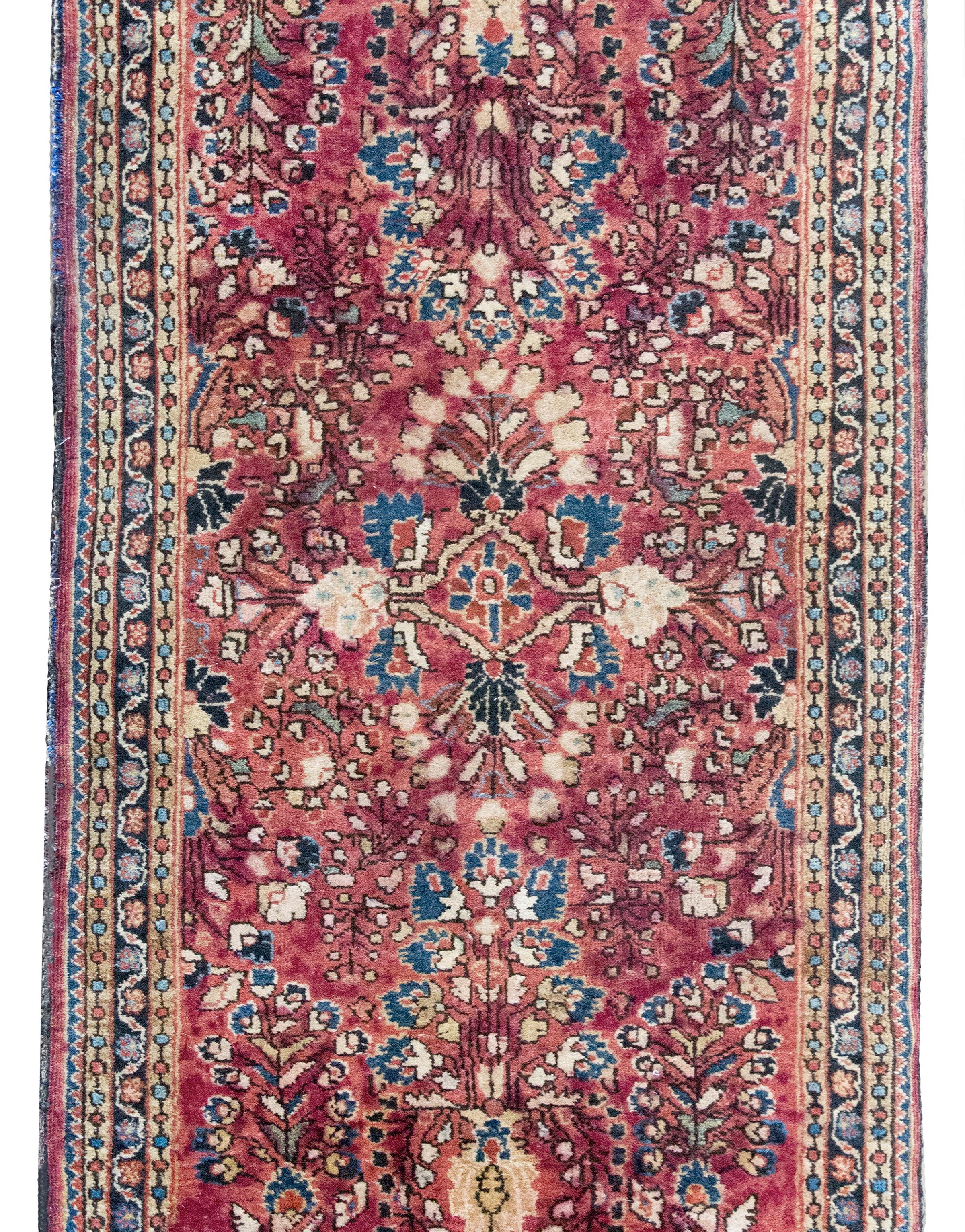 Tappeto Sarouk persiano tradizionale dell'inizio del XX secolo con un motivo floreale a specchio con una miriade di fiori e tralci che scorrono, tessuto in lana color mirtillo rosso, indaco chiaro e scuro, crema e rosa e circondato da un bordo