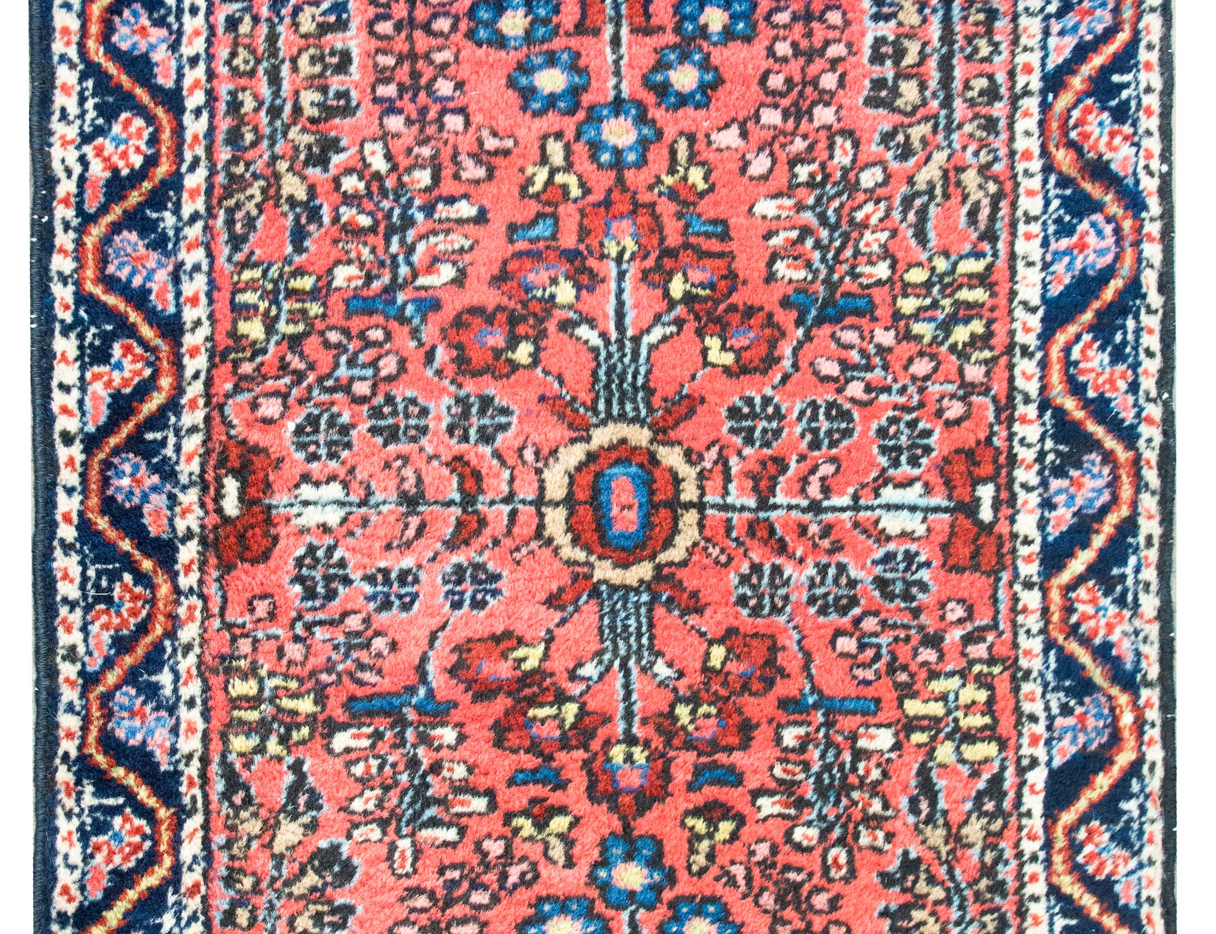 Ein auffälliger, zierlicher persischer Sarouk-Teppich aus dem frühen 20. Jahrhundert mit einem gespiegelten Blumenmuster mit unzähligen Blumenarten und -büscheln, umgeben von einer einfachen Bordüre mit Ranken und Blumen, gewebt in verschiedenen