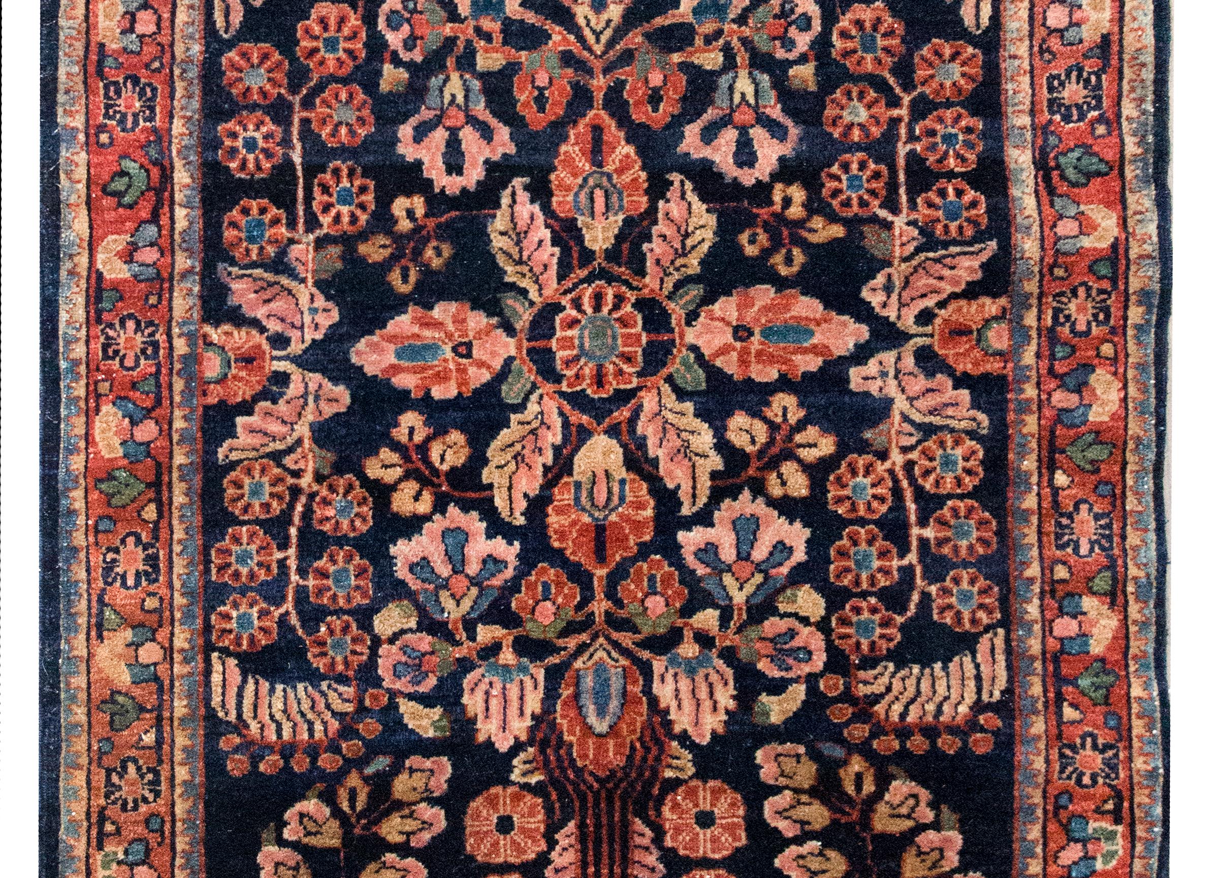 Un bellissimo tappeto Sarouk persiano dell'inizio del XX secolo con un motivo floreale a specchio con una miriade di grappoli floreali sul campo e circondato da un dolce bordo a motivi floreali, il tutto tessuto in varie tonalità di lana color