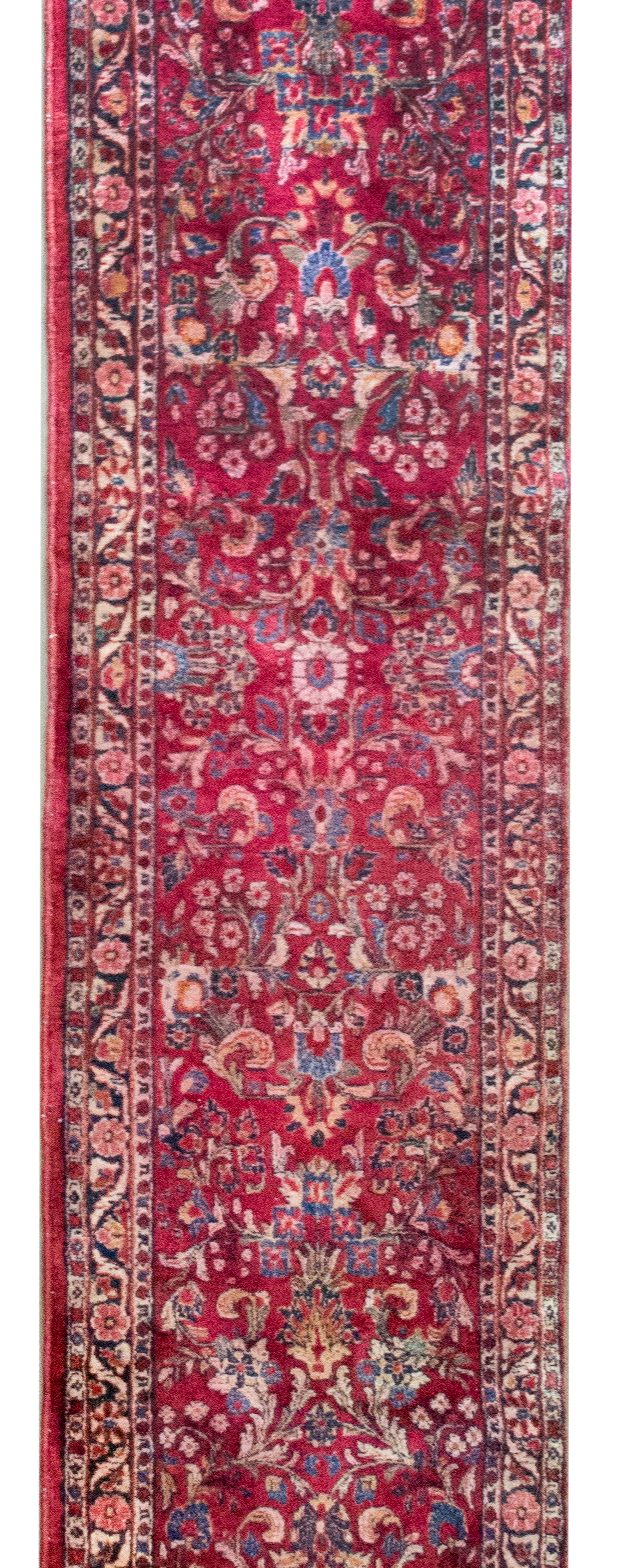 Questo runner persiano Sarouk dei primi del Novecento è un esempio accattivante di artigianato tradizionale e design senza tempo. Caratterizzato da un classico motivo Sarouk, il suo campo è ornato da ripetuti grappoli floreali a specchio, che creano