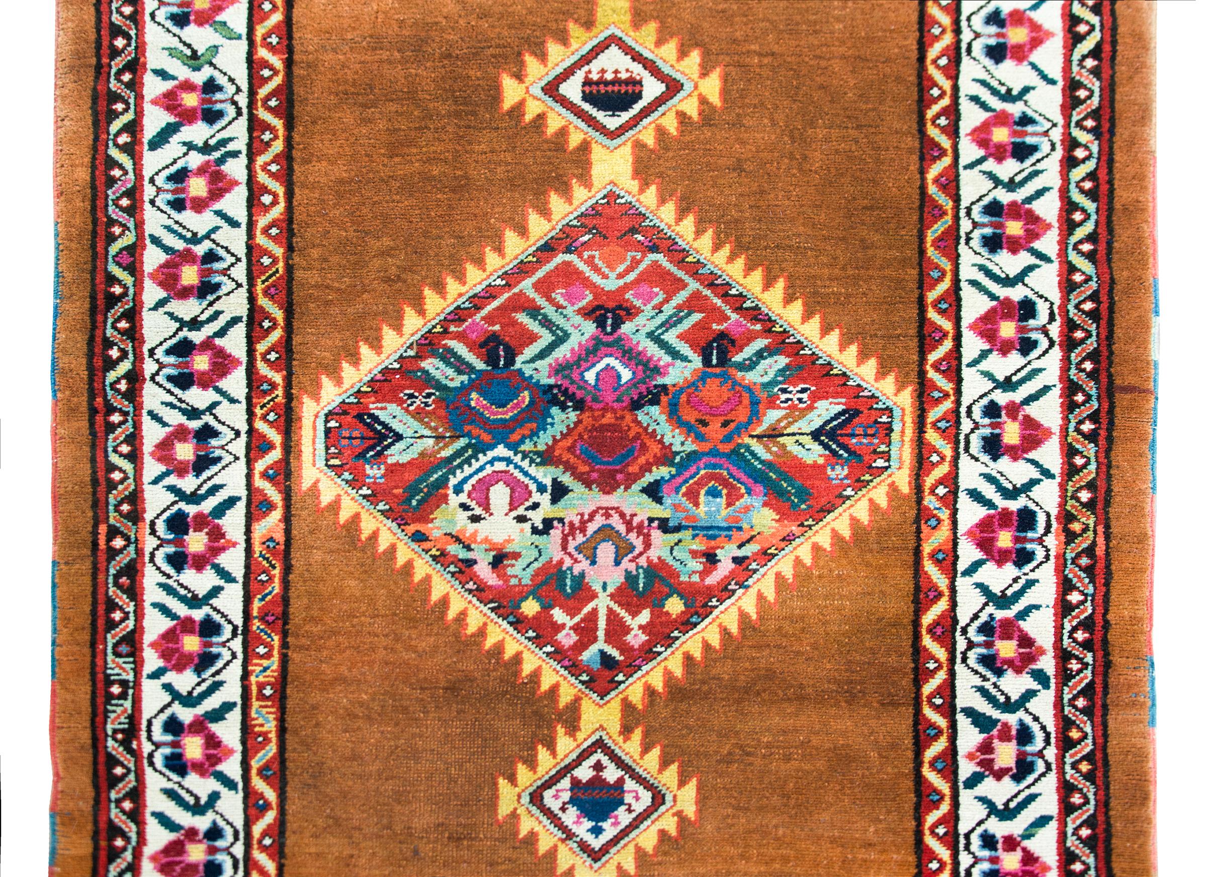 An incredible and stylish early 20th century Persian Serab runner with three large diamond medallions each woven with large-scale stylized flower clusters woven in myriad bold colors and all set against a natural camel wool ground.  The border is