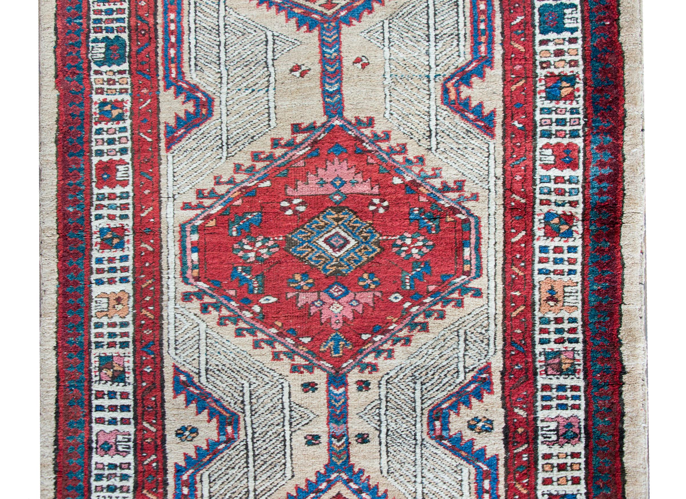 A remarkable early 20th century Persian Serab runner with a large crimson central diamond medallion flanked by two more smaller diamond medallions with stylized floral details, and living amidst a field more stylized flowers and scrolling vines,
